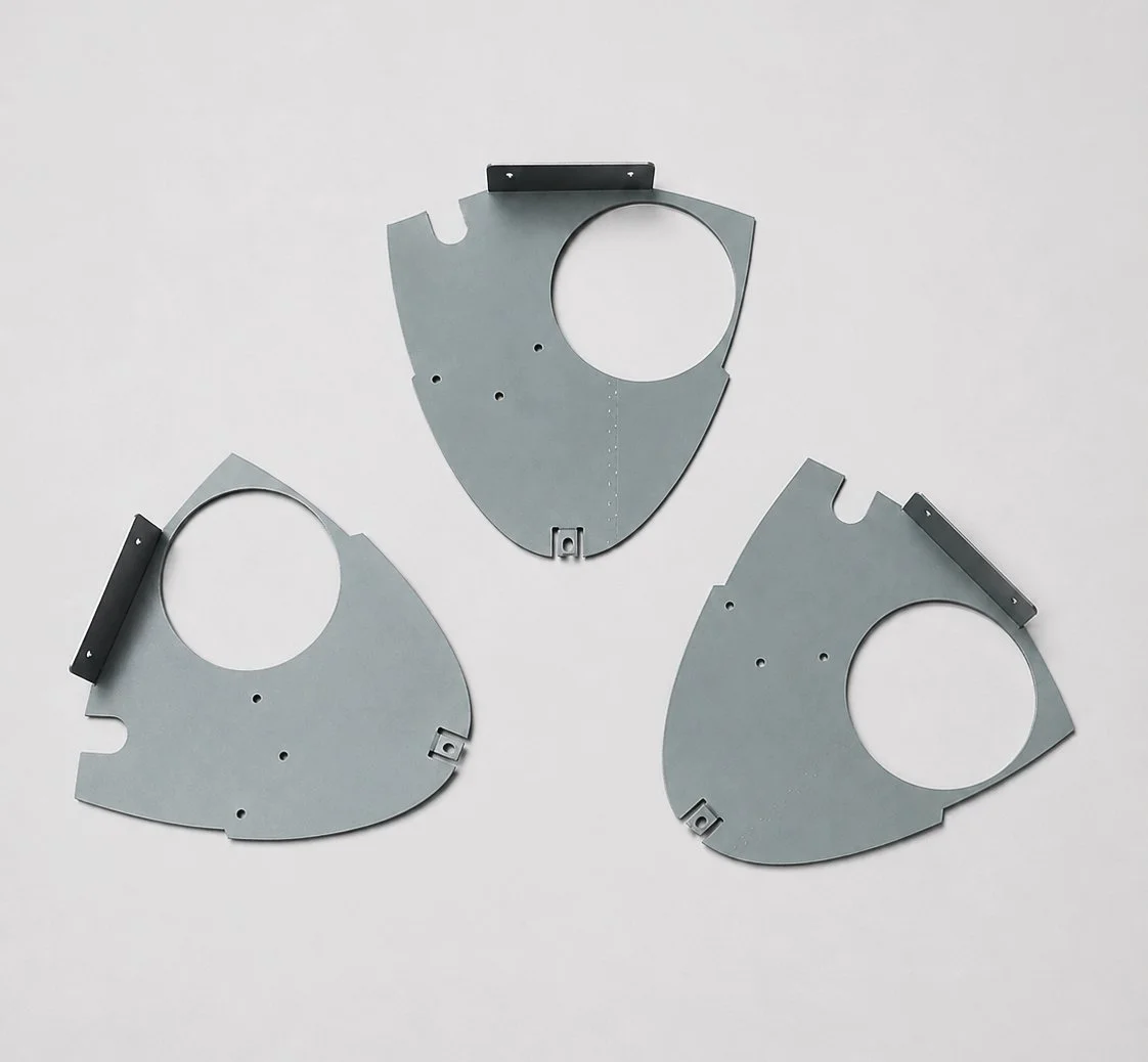 Three gray metal circular brackets with black tabs arranged on a light gray background.