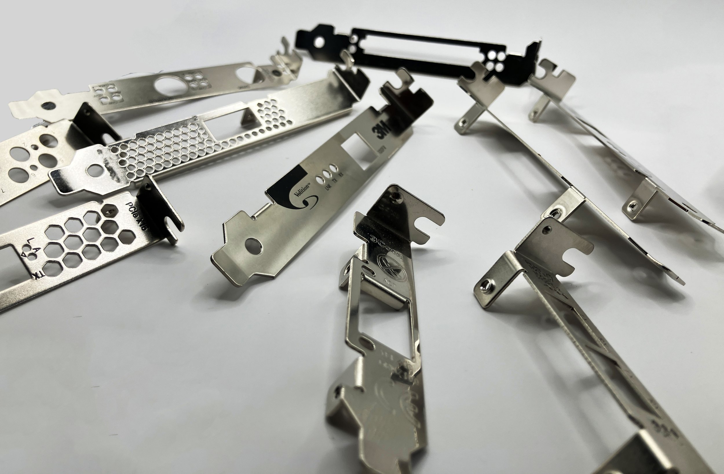 A collection of metal computer hardware brackets and mounts arranged on a white surface.