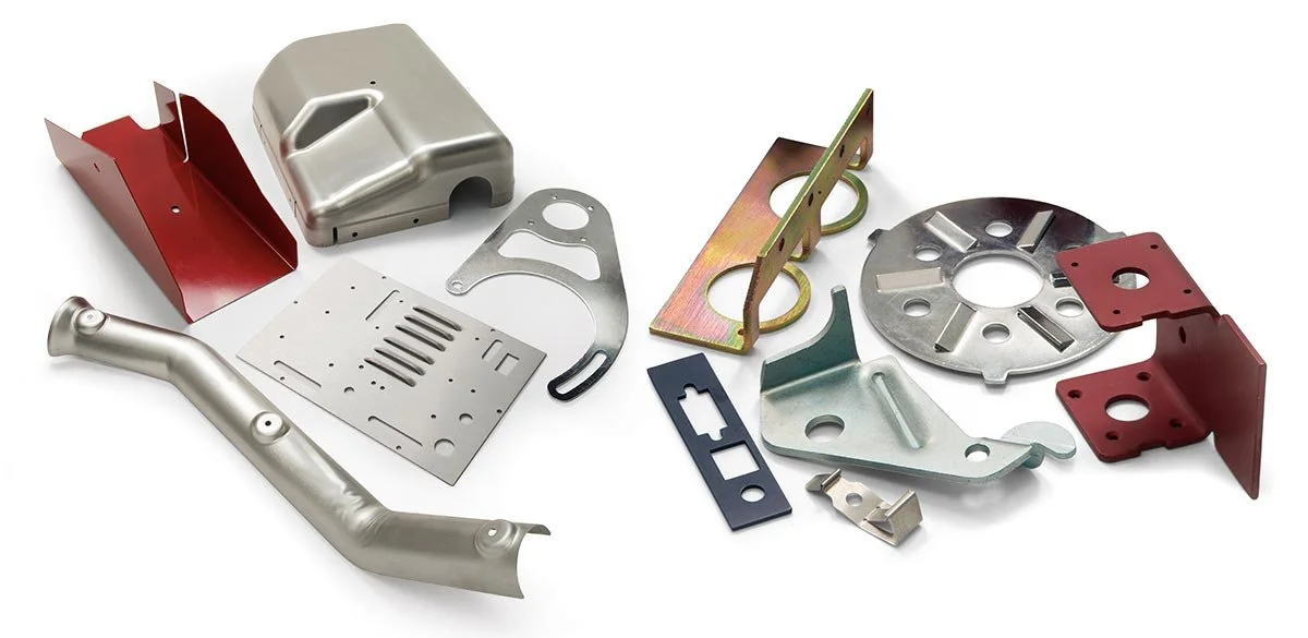 Collection of metallic and painted metal parts and brackets, likely automotive or machinery components, arranged on a white surface.