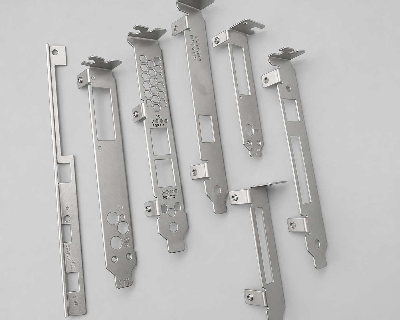 Six metallic metal plates with various cutouts and engraved markings, laid out on a white background.