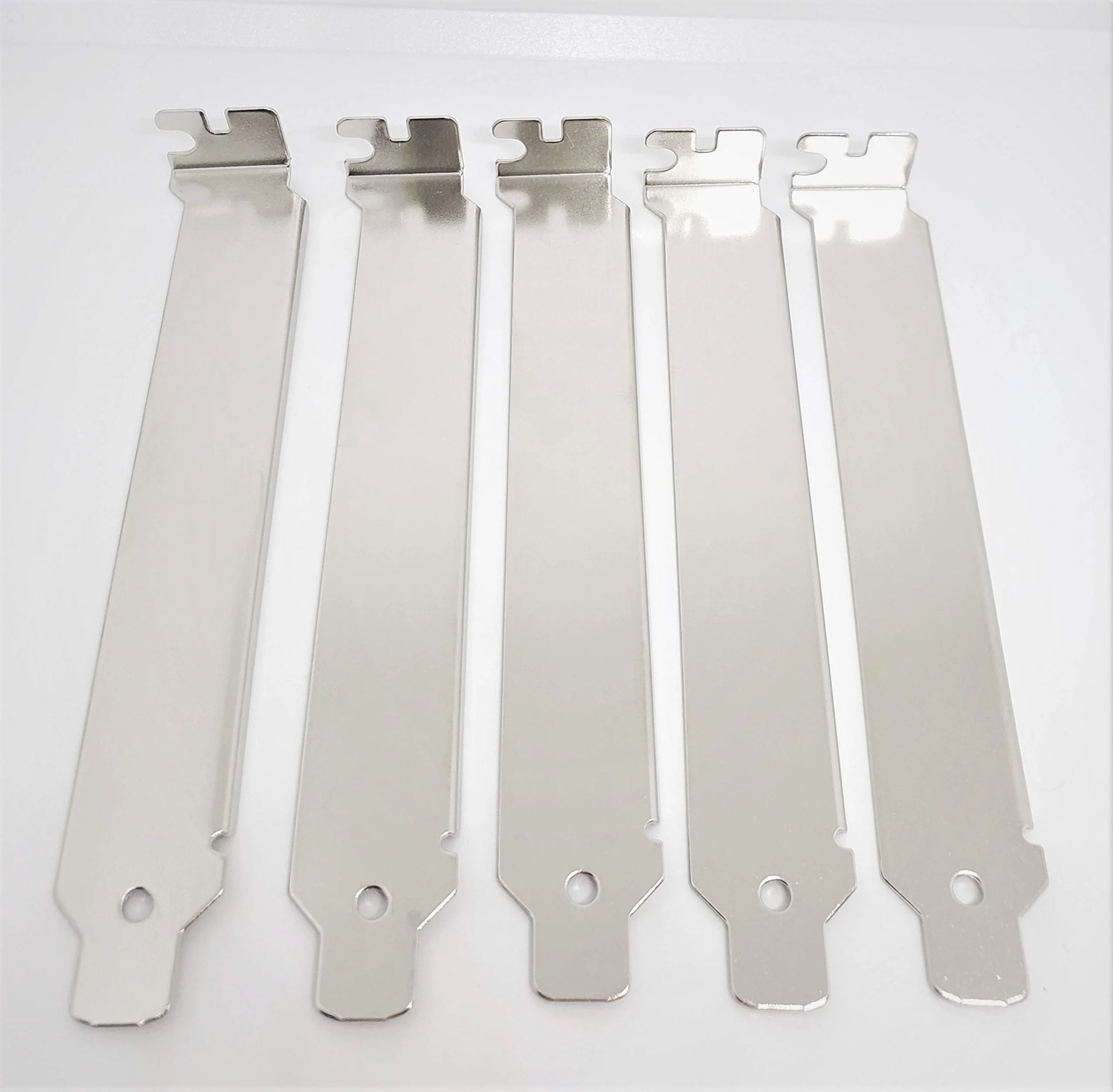 Five silver-colored razor blade guards with holes at the bottom, arranged in a row on a white surface.
