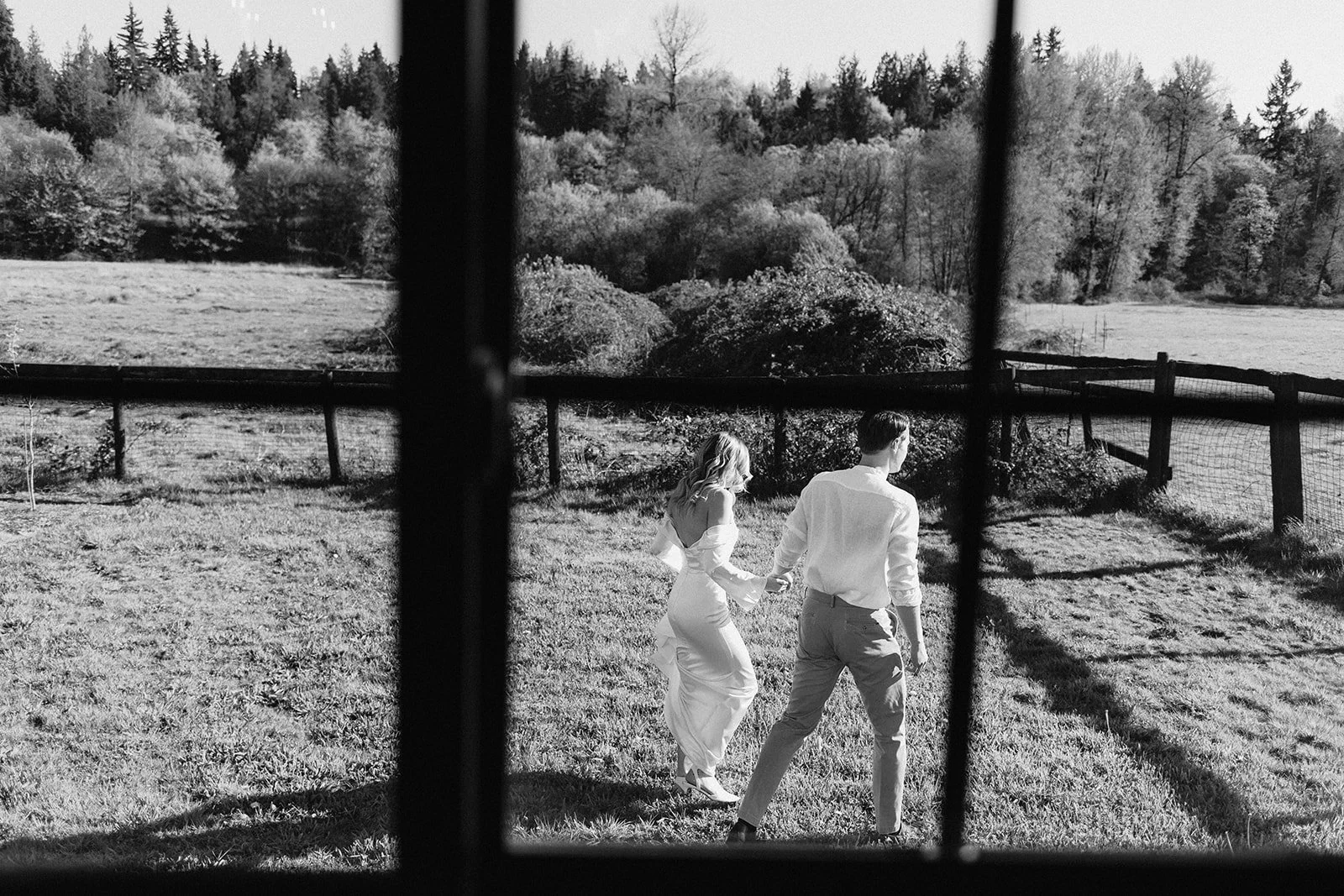 Bride and groom holding hands walking through a yard with trees in the background