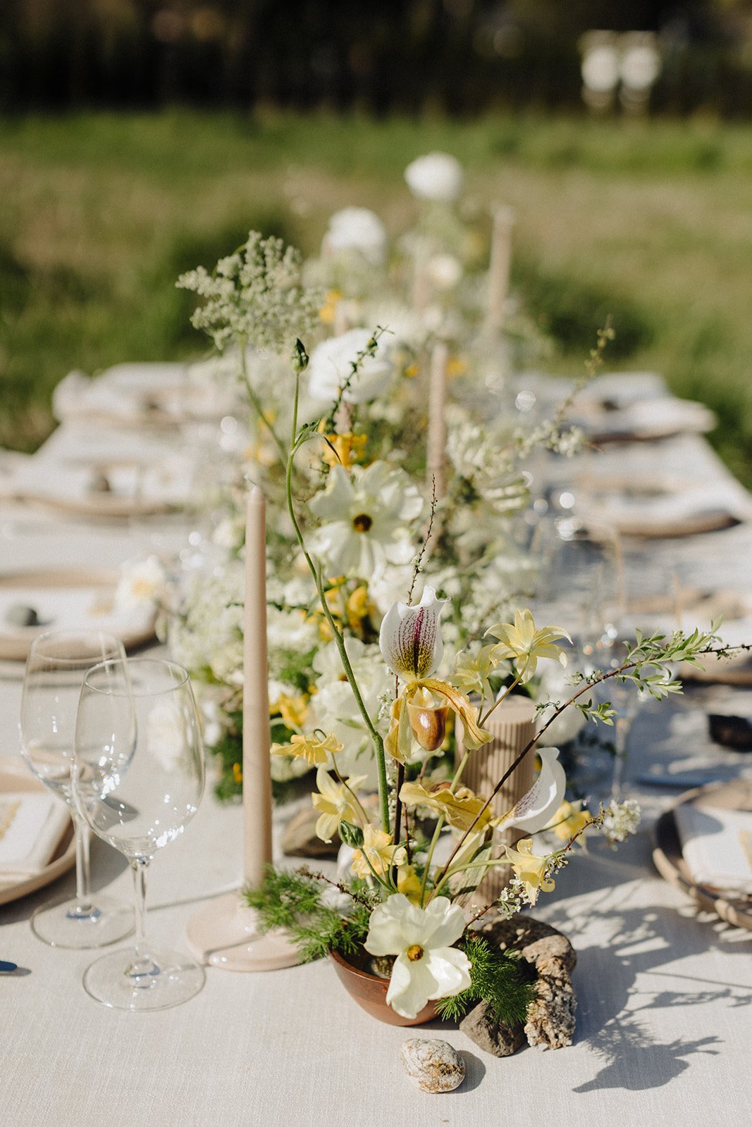 Fresh summer florals with buttery yellow blooms and greenery on table