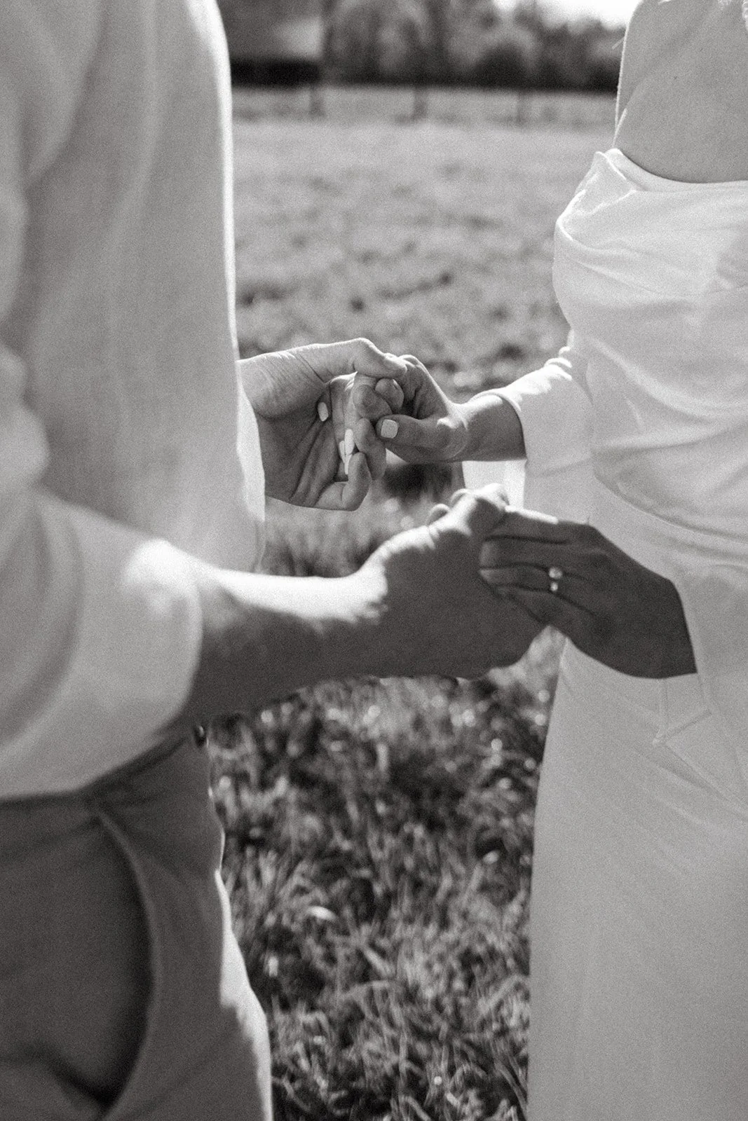 Bride and groom holding hands during their wedding portrait session in a field