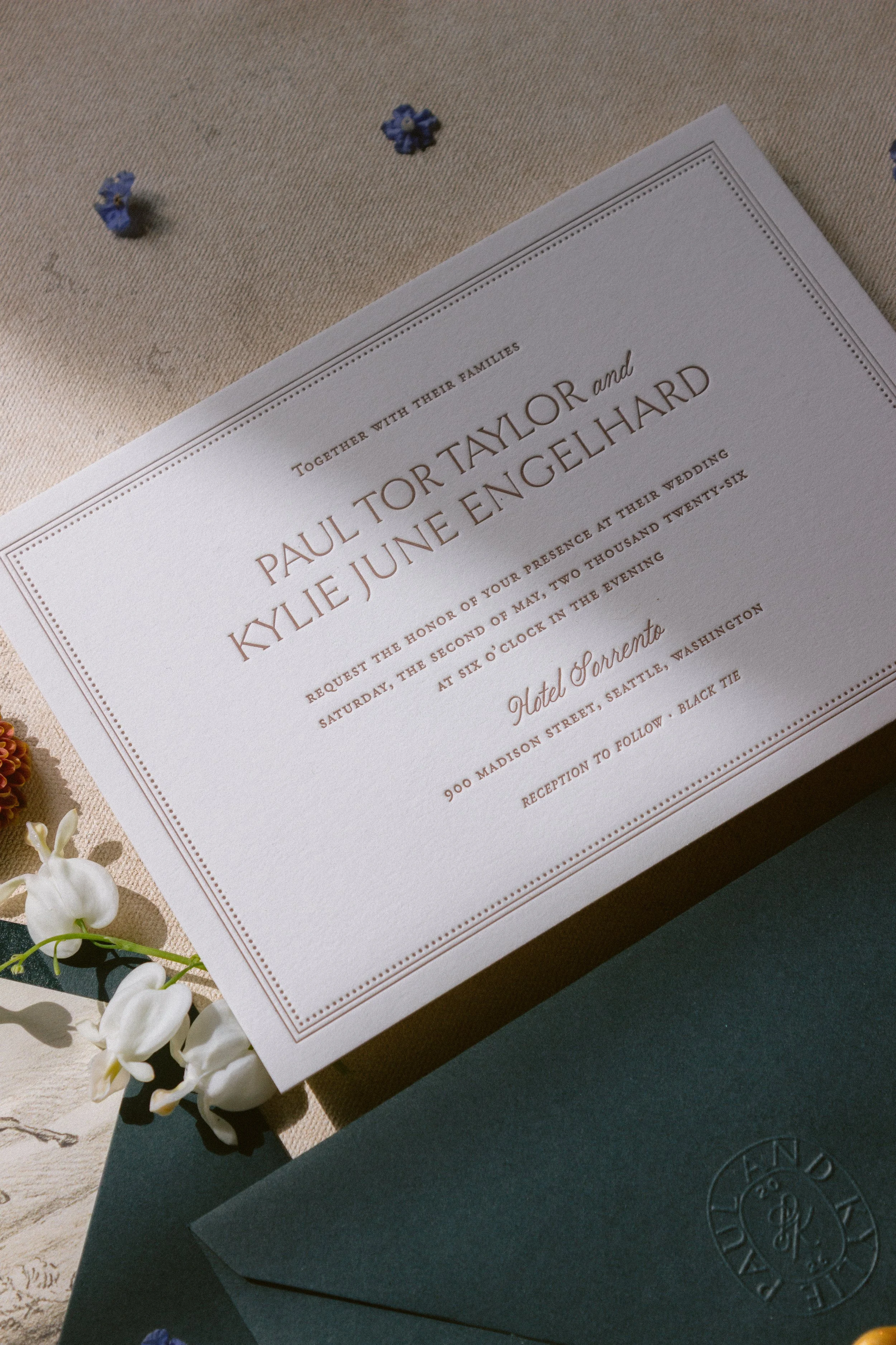 Wedding invitation with floral decorations and a black envelope.