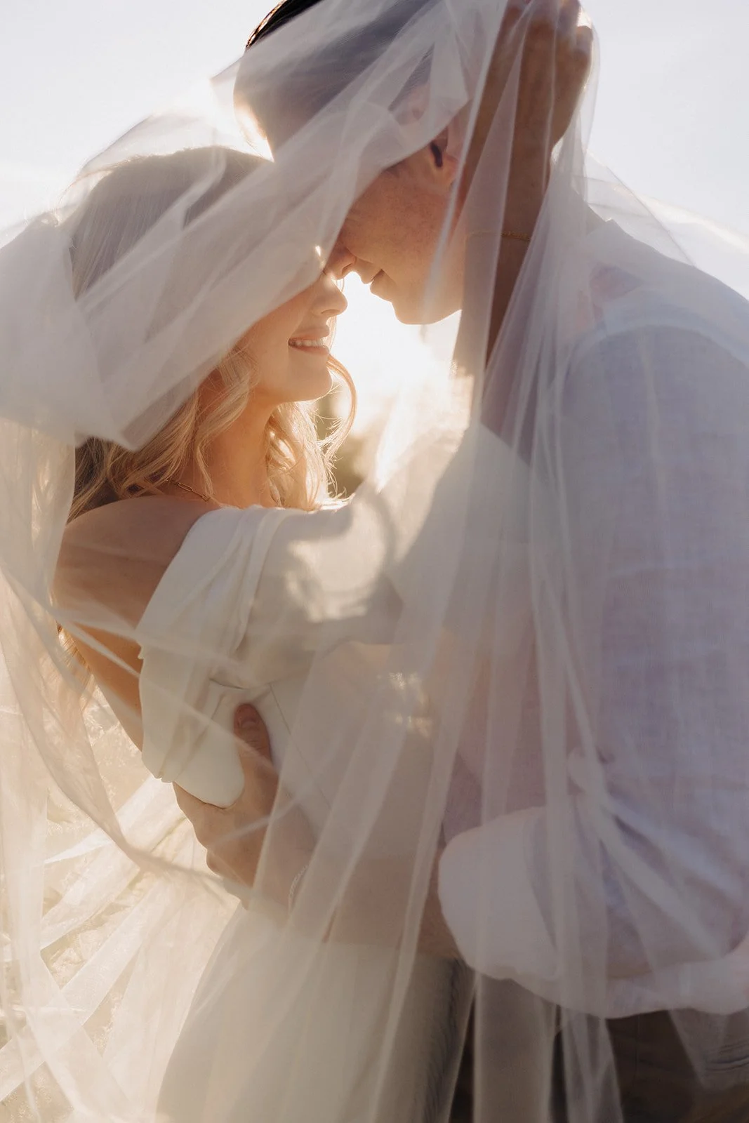 Bride and groom portrait with veil over their heads