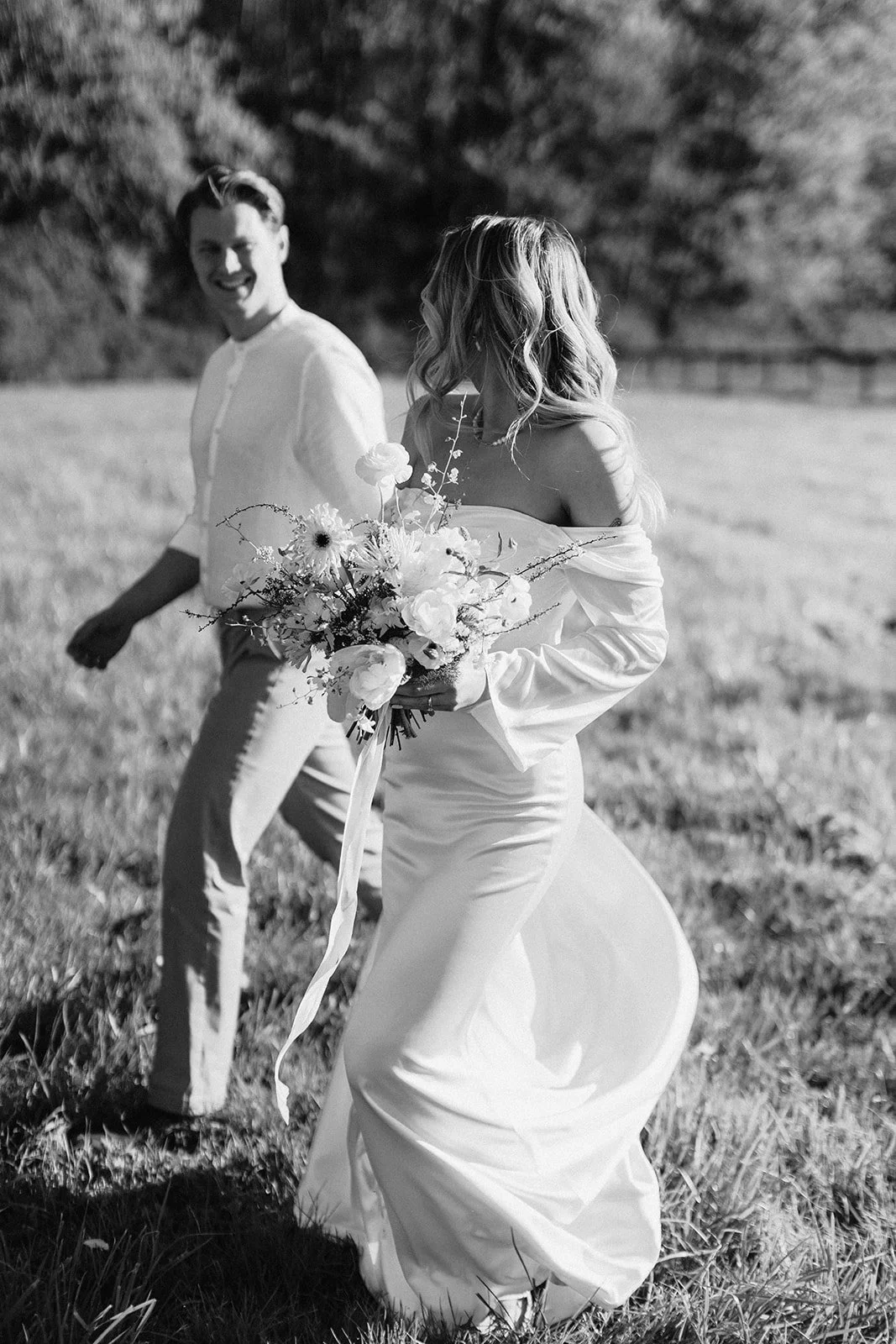 Bride and Groom walking through a field holding the bridal wildflower bouquet