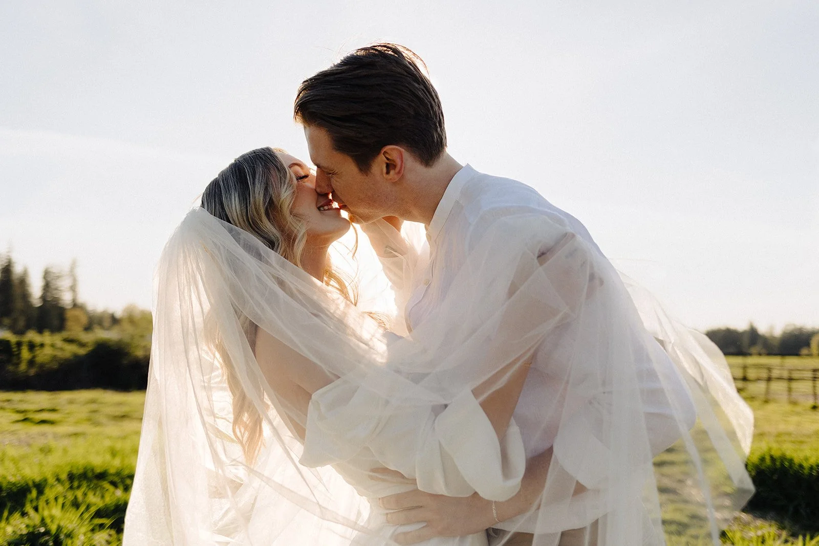 Bride and groom in a sunny field at Bannan House Farm with lush grass