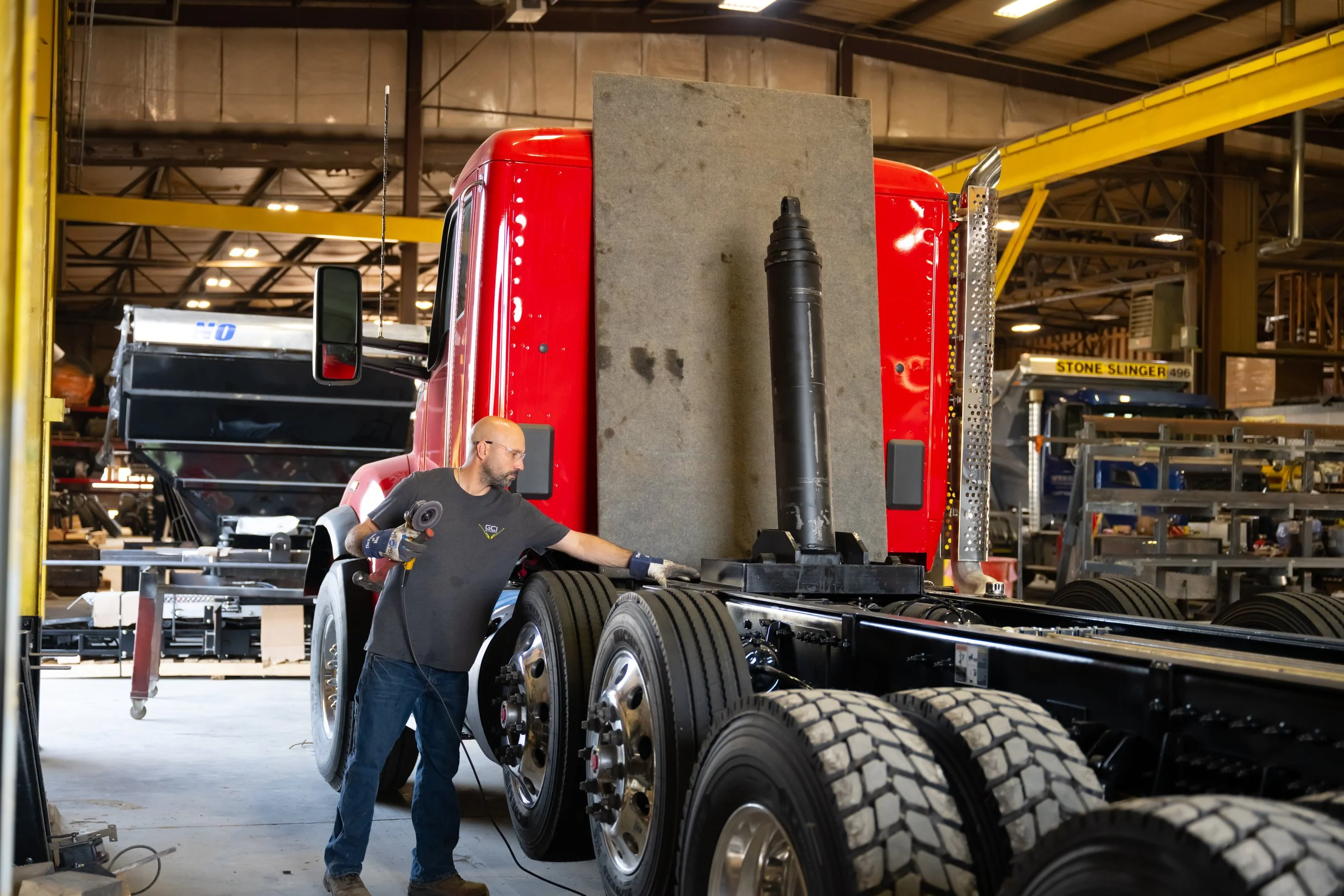 A worker using power tools on a 16 wheeler