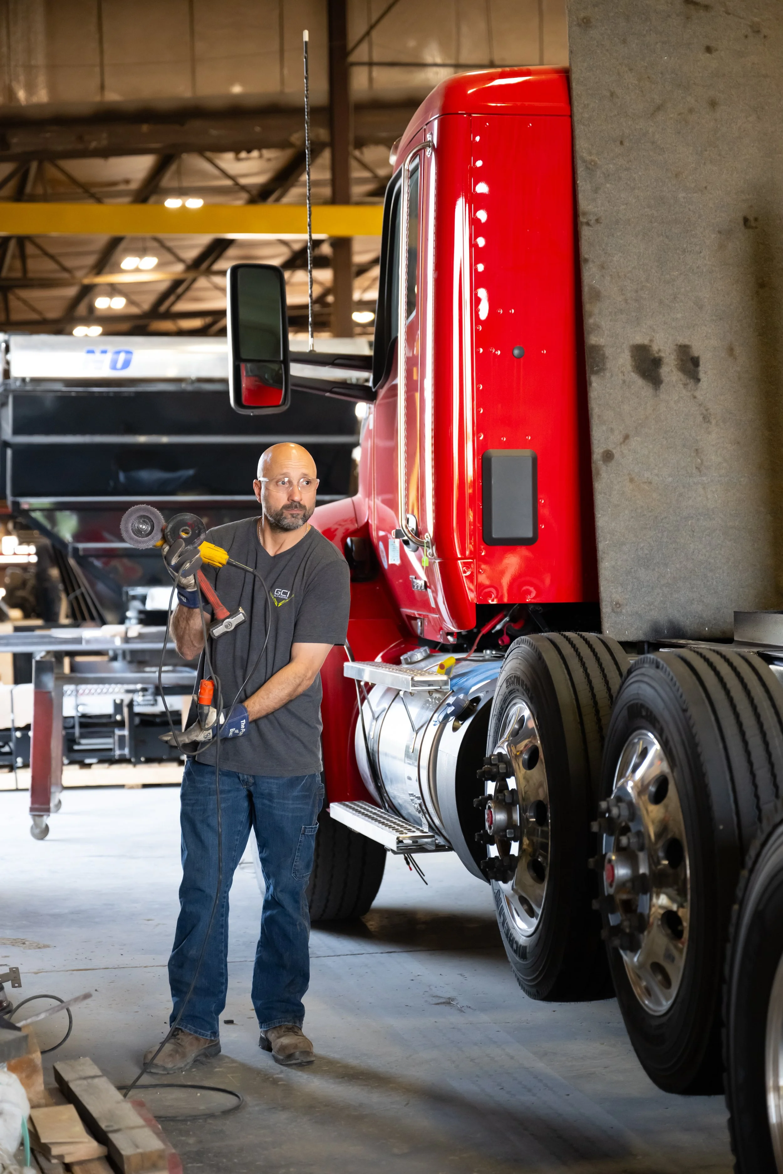 An employee with safety goggles handling power tools near a GCI truck