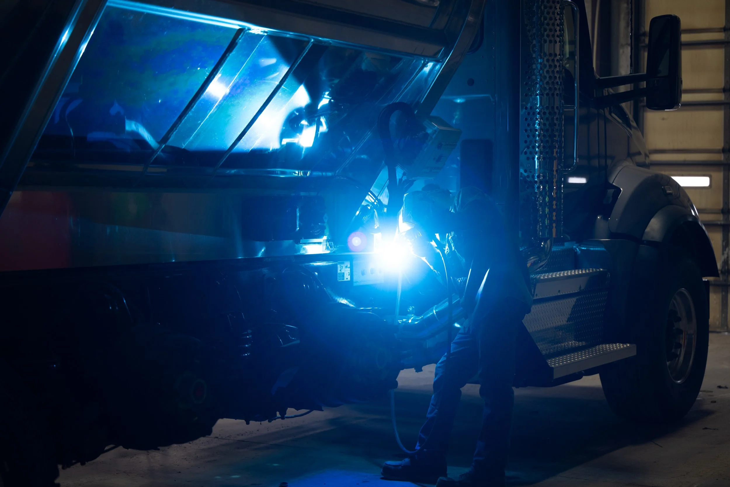 An employee actively welding a GCI truck