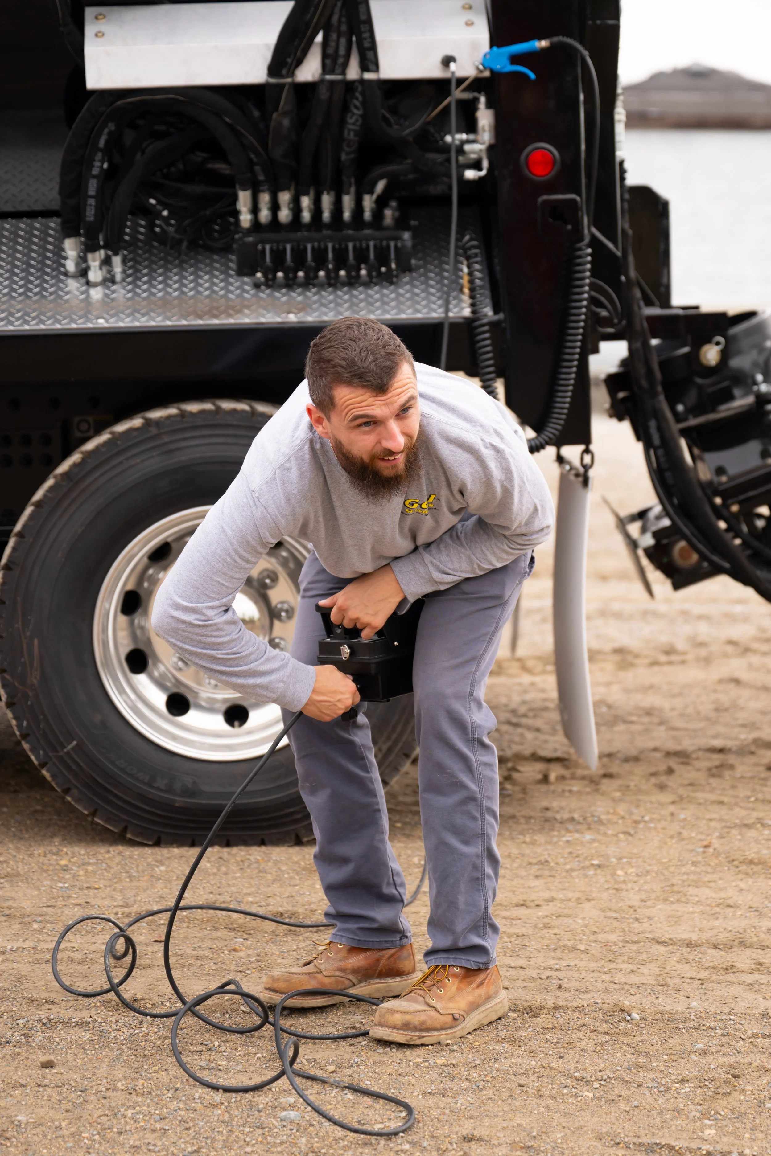 A worker leaning down and working with wires from a truck
