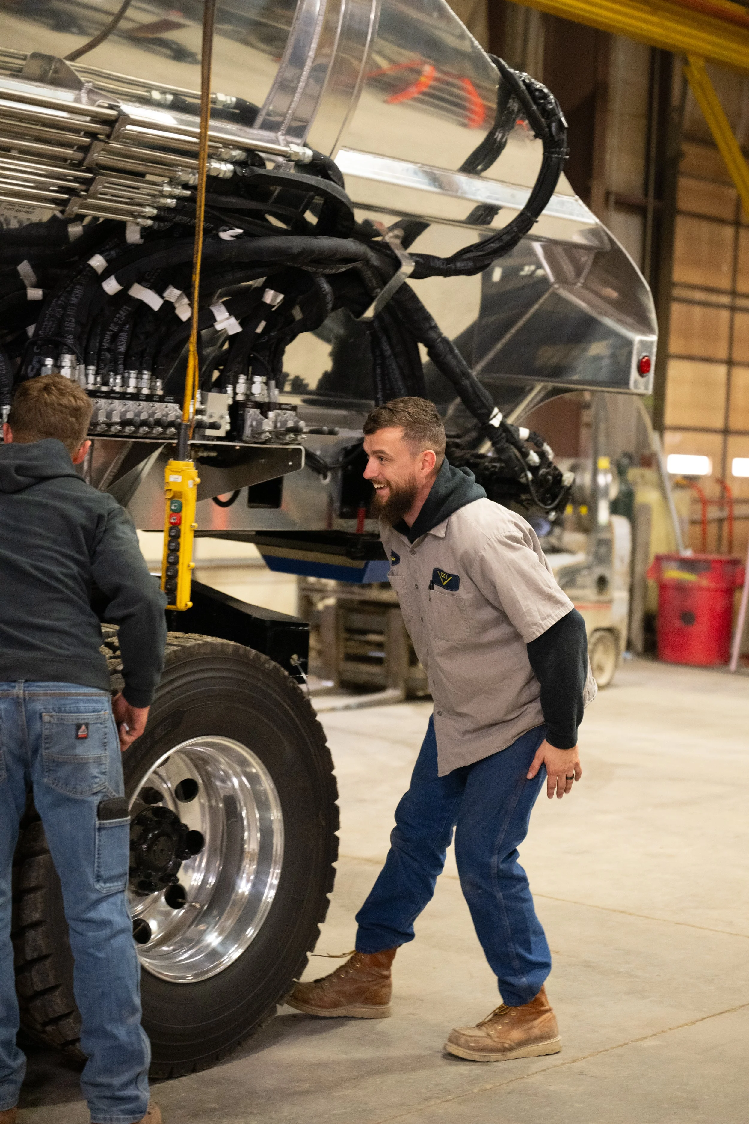Two workers smiling while working on a truck