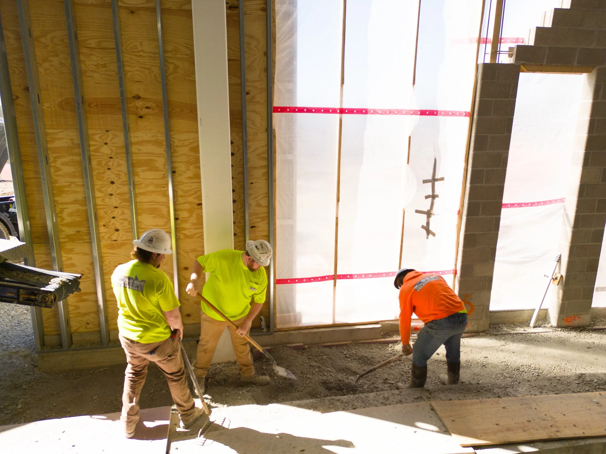 Three men evening out the material placed in a building
