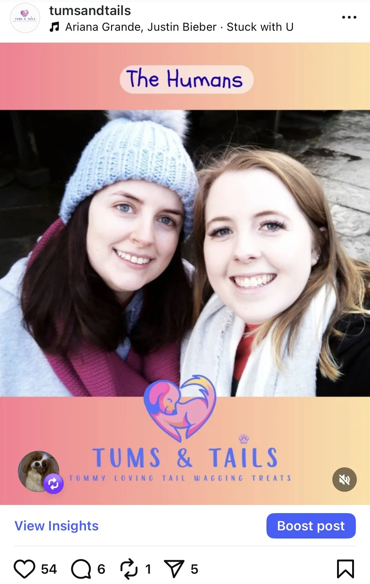 Two young women smiling, one wearing a gray knit hat with a pom-pom, and the other with long, light brown hair, both dressed warmly, outdoors.