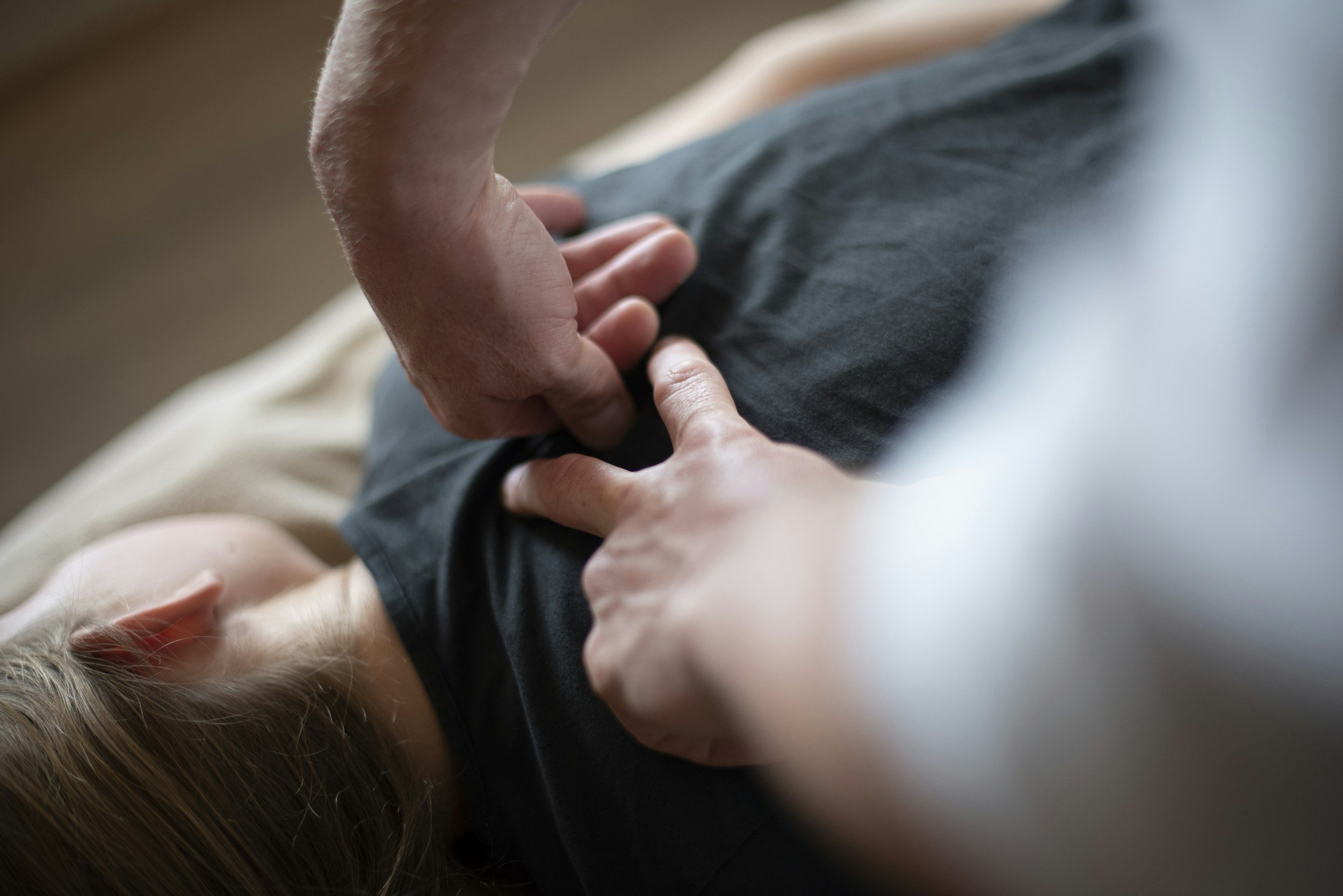 Close-up of a person performing manual therapy on a patients back.