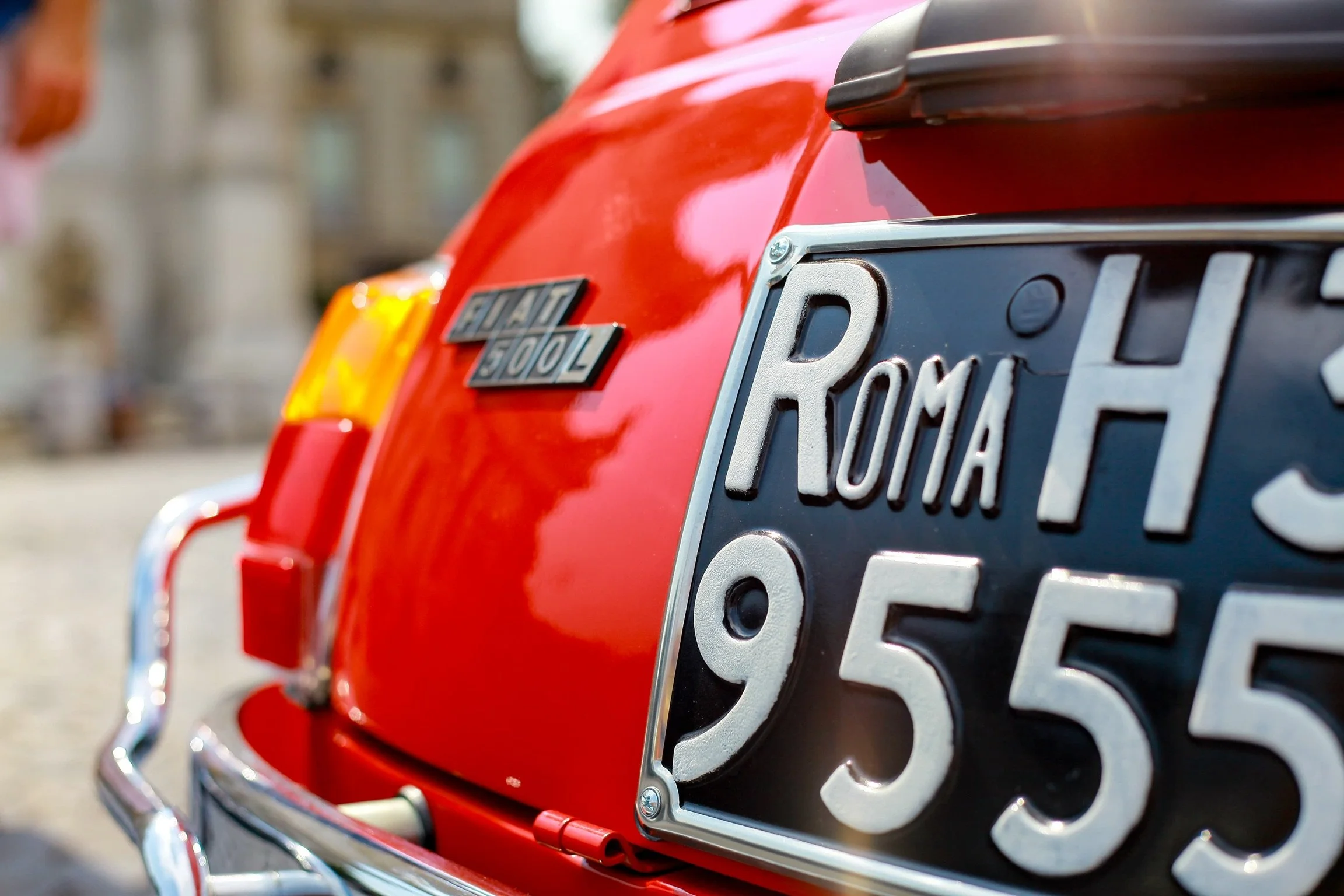 Particolare posteriore di una macchina rossa con targa italiana e badge Fiat 500L.