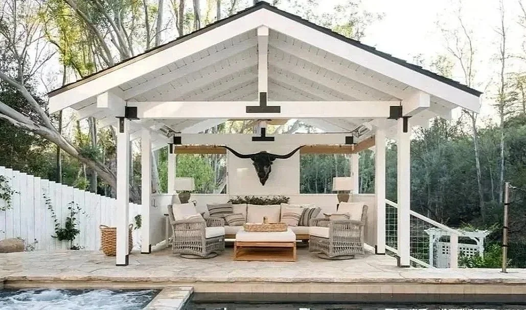 Outdoor patio with white wooden roof, wicker chairs, a sectional sofa, and a mounted longhorn skull