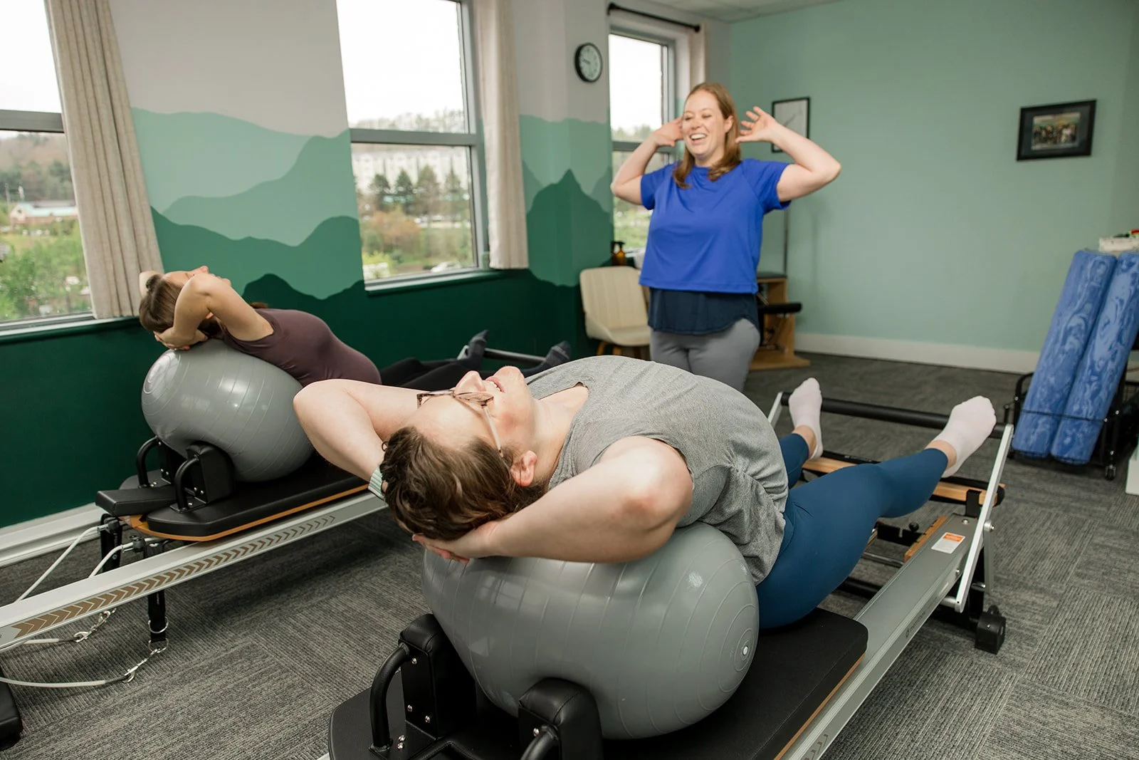 woman teaching semiprivate pilates session on the reformer in a room that is calming and peaceful