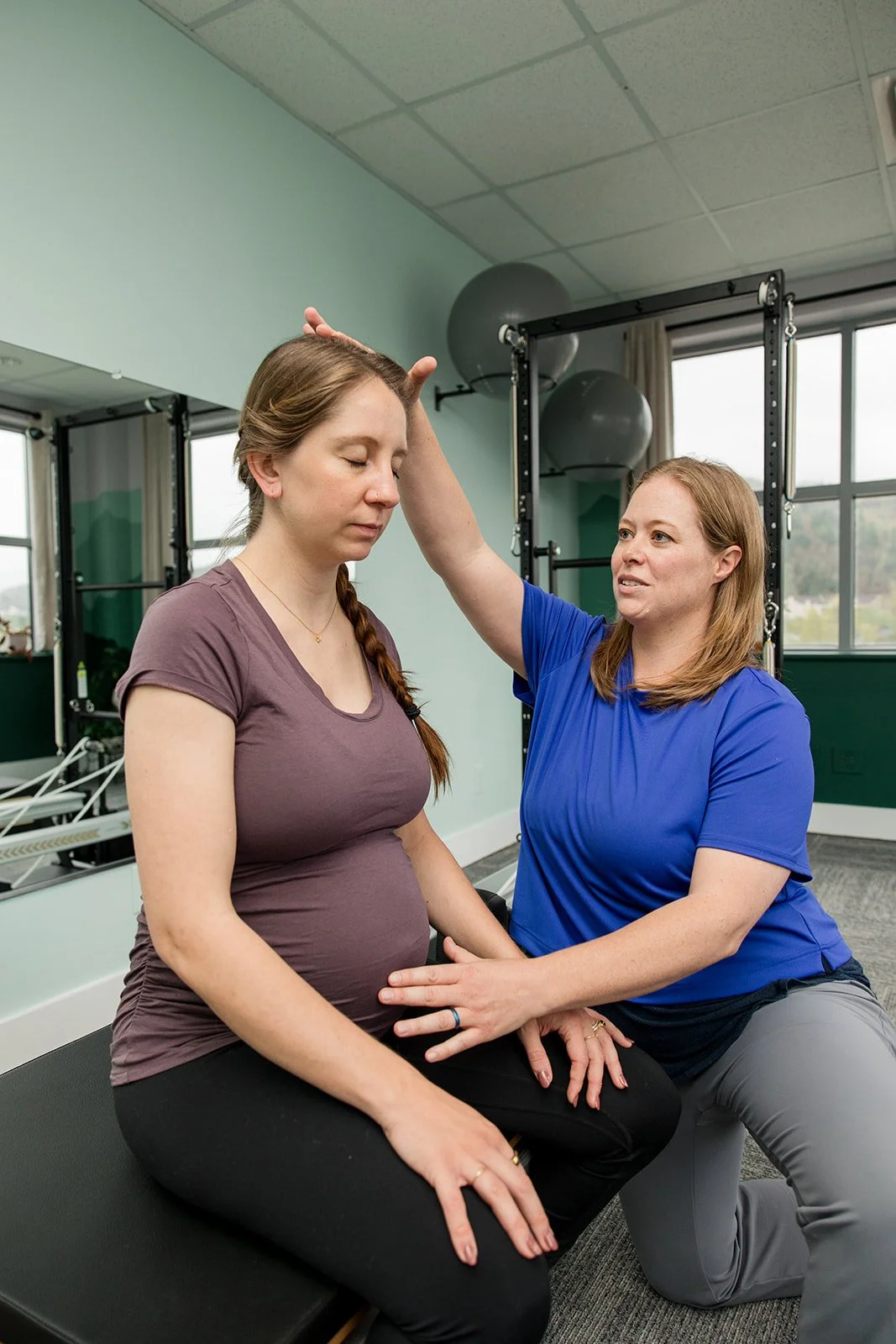 pilates instructor giving tactile cues to pregnant women with eyes closed