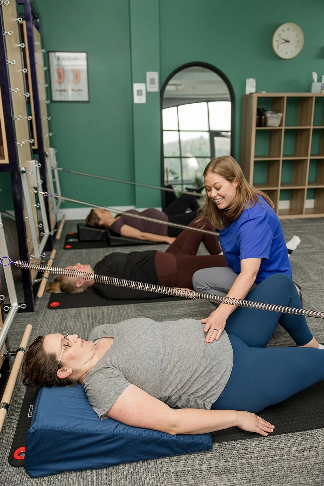 pilates instructor using fingers to cue abdominal engagement in pregnant mom lying on wedge pillow