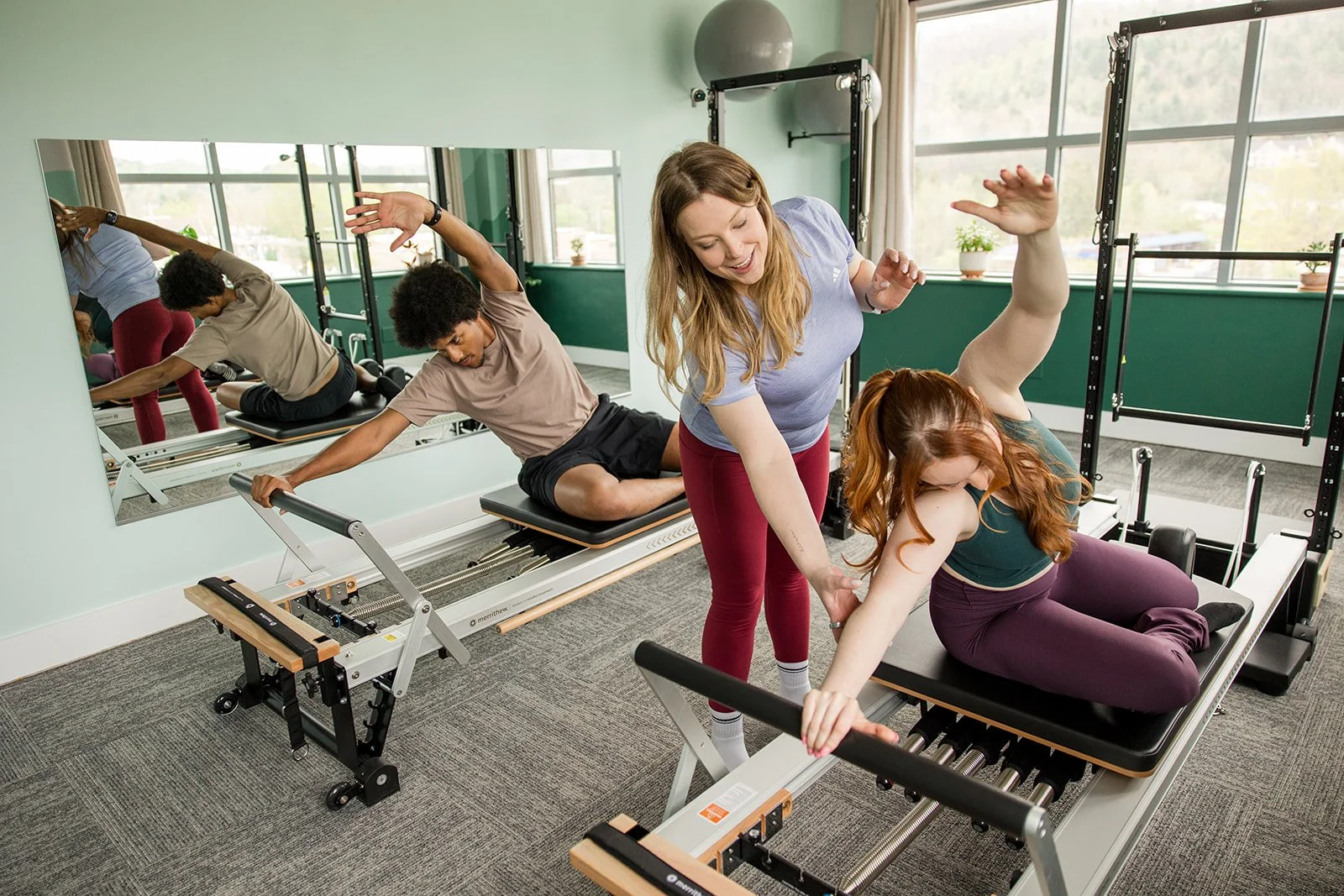 woman teaching couple on the pilates reformer