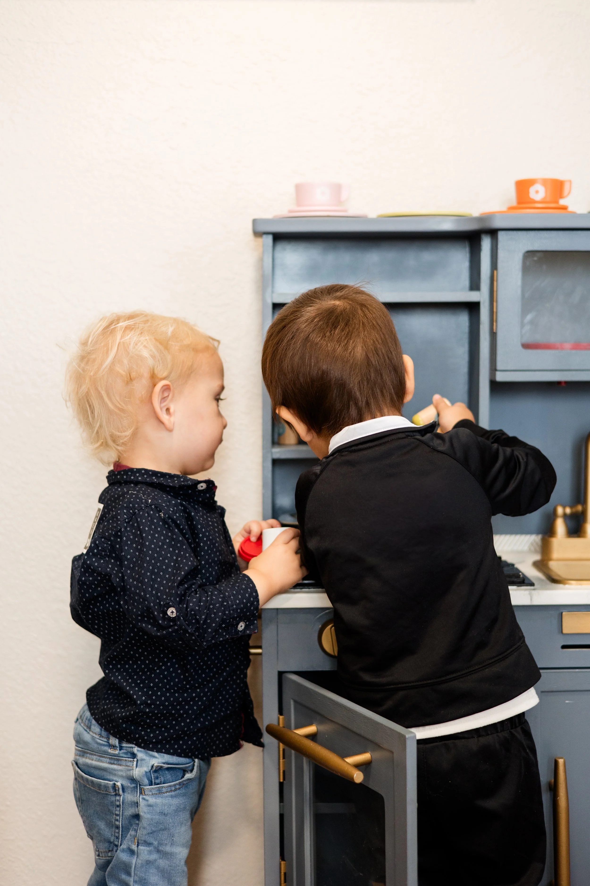 Two children playing with a toy kitchen set.