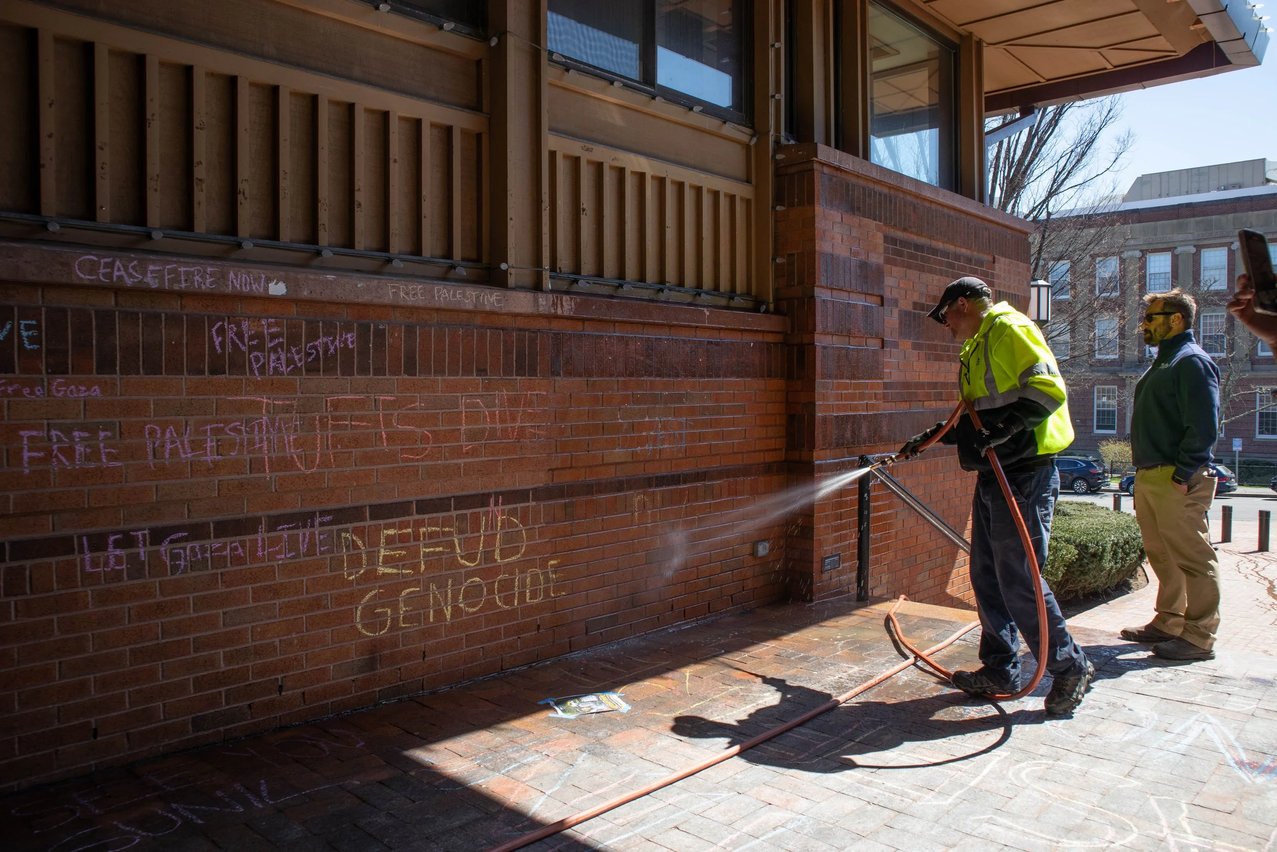 Tufts facility workers remove students' chalk markings.