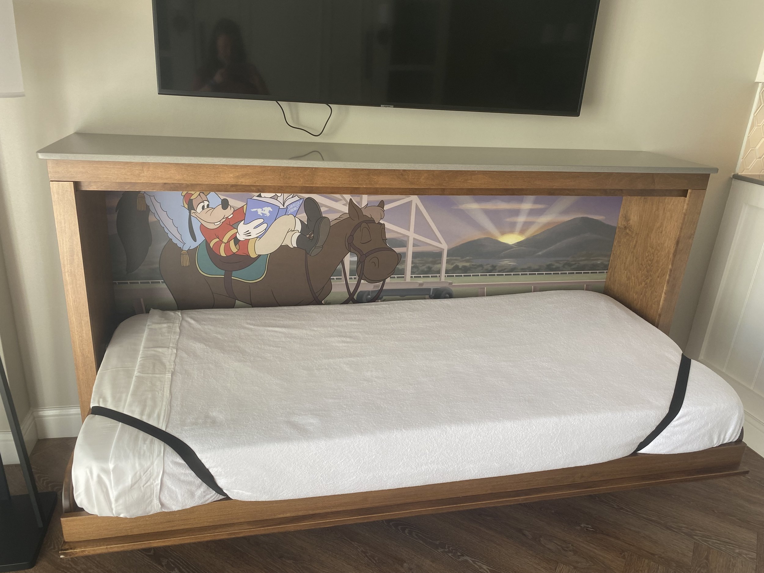 Wooden bed with a bumper featuring Goofy reading a book against a scenic background with mountains and sunrise.