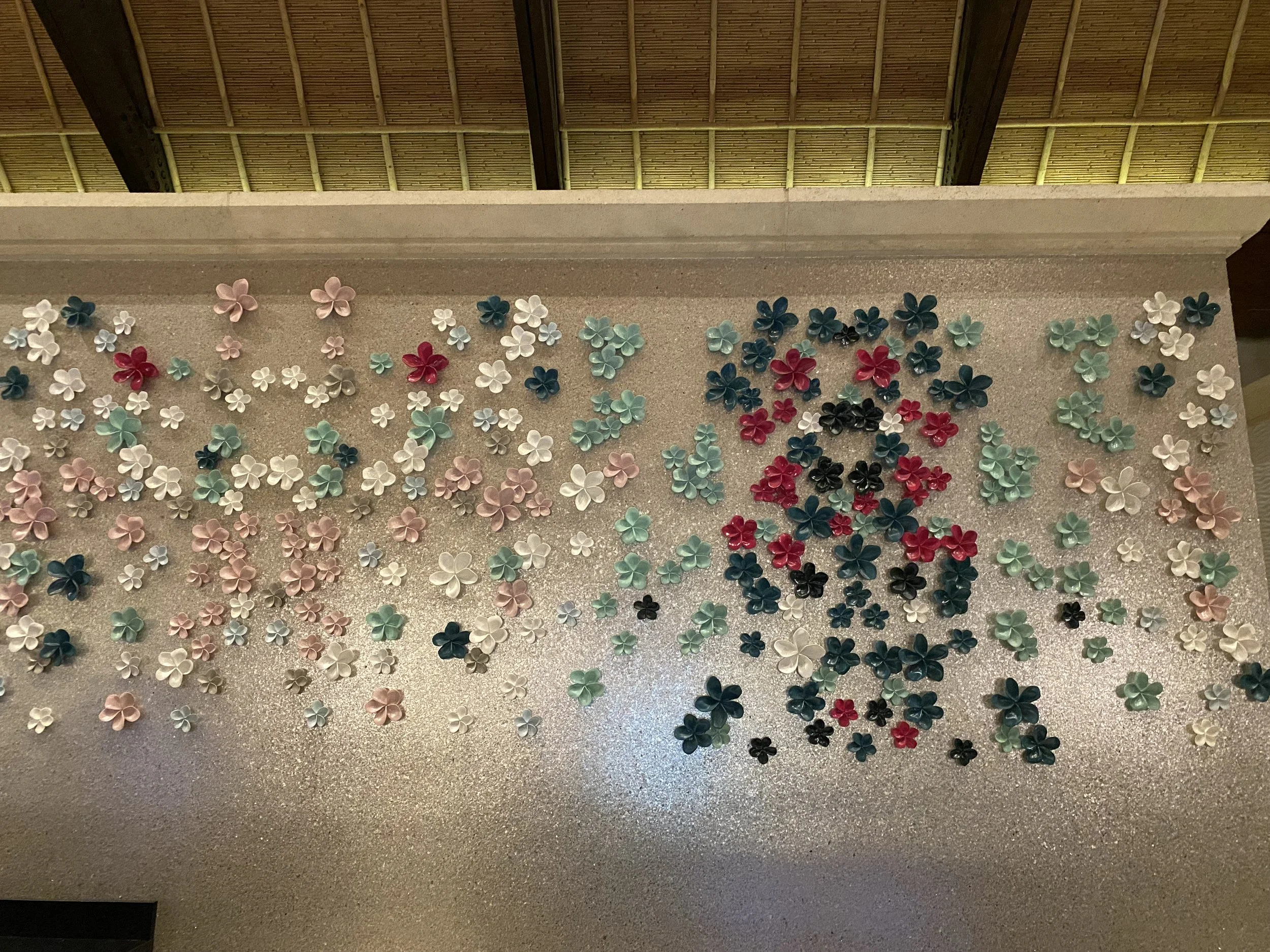 Decorative wall with colorful flower-shaped decorations arranged to form text and a panda face, seen from above.