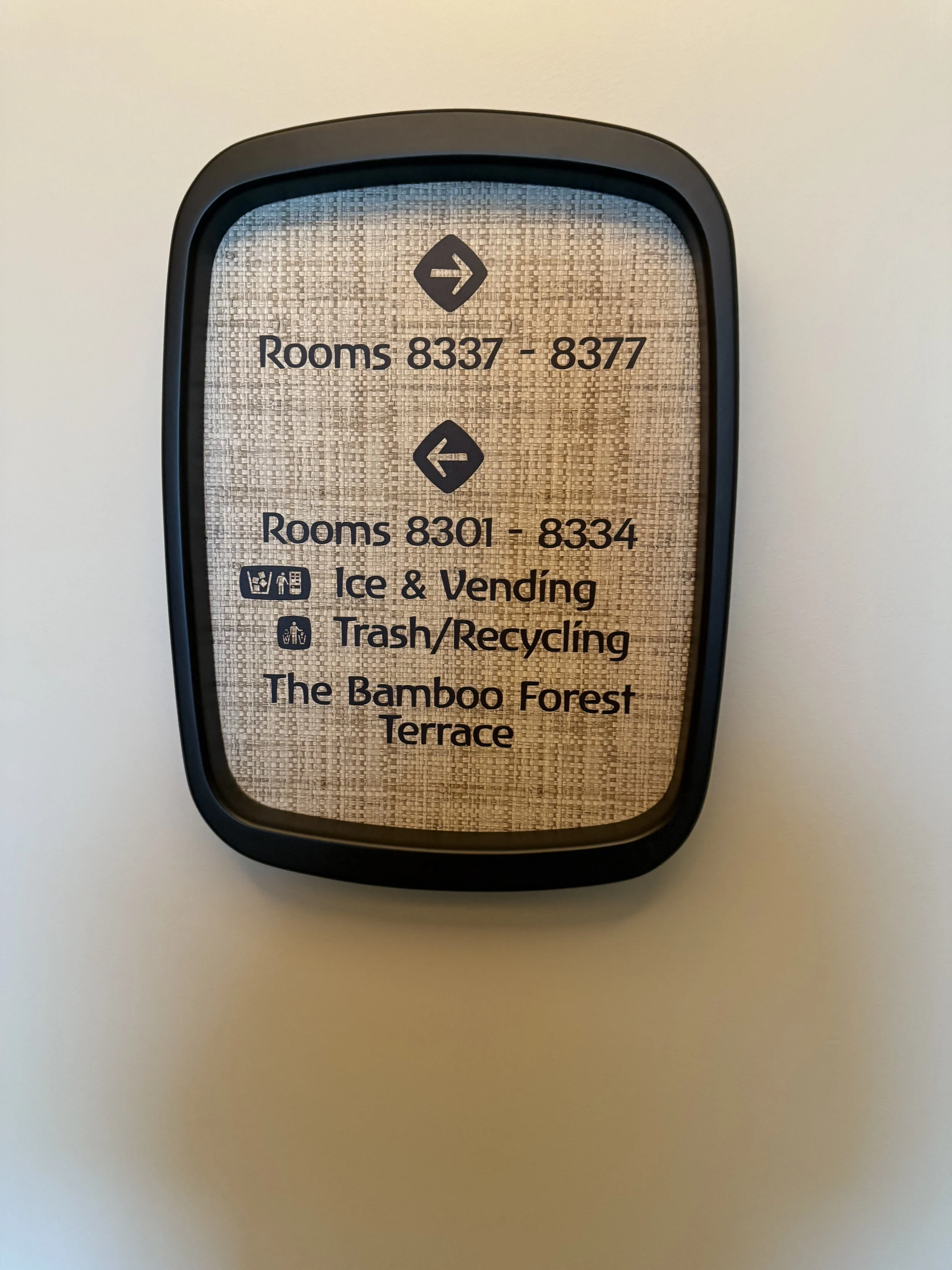 Room directory sign with room ranges, and icons indicating ice vending and trash recycling, on a textured beige background.