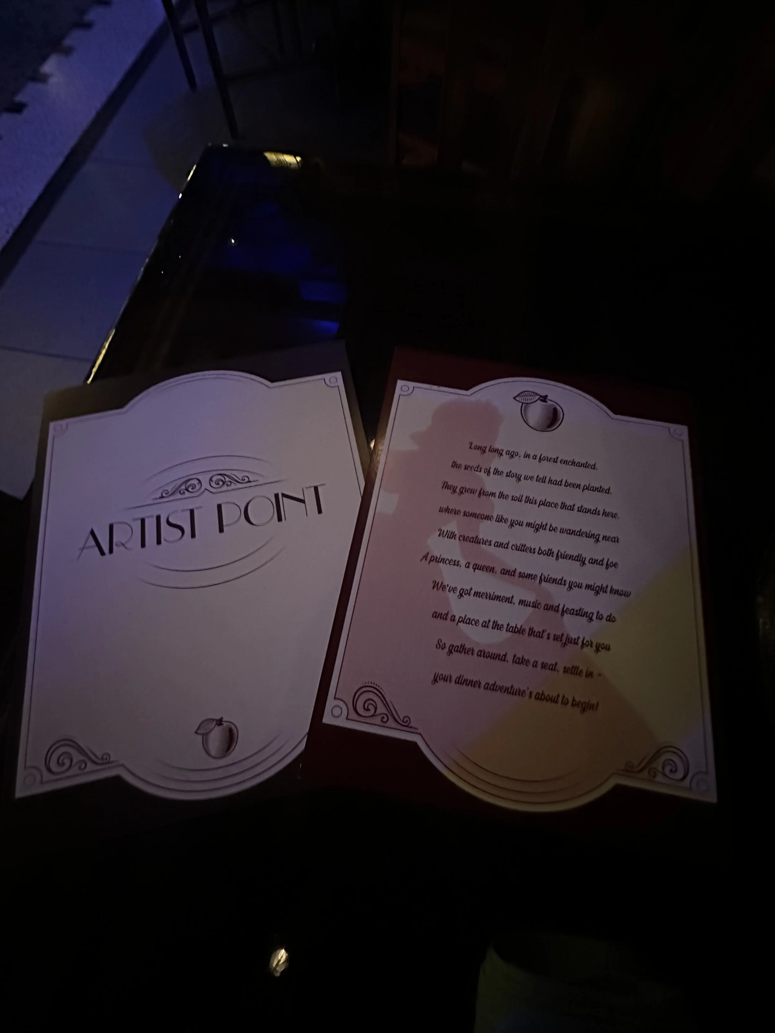 An open booklet with the title 'ARTIST POINT' and some decorative elements, alongside a story page with text about a forest enchanted, featuring a small illustration of a peach.