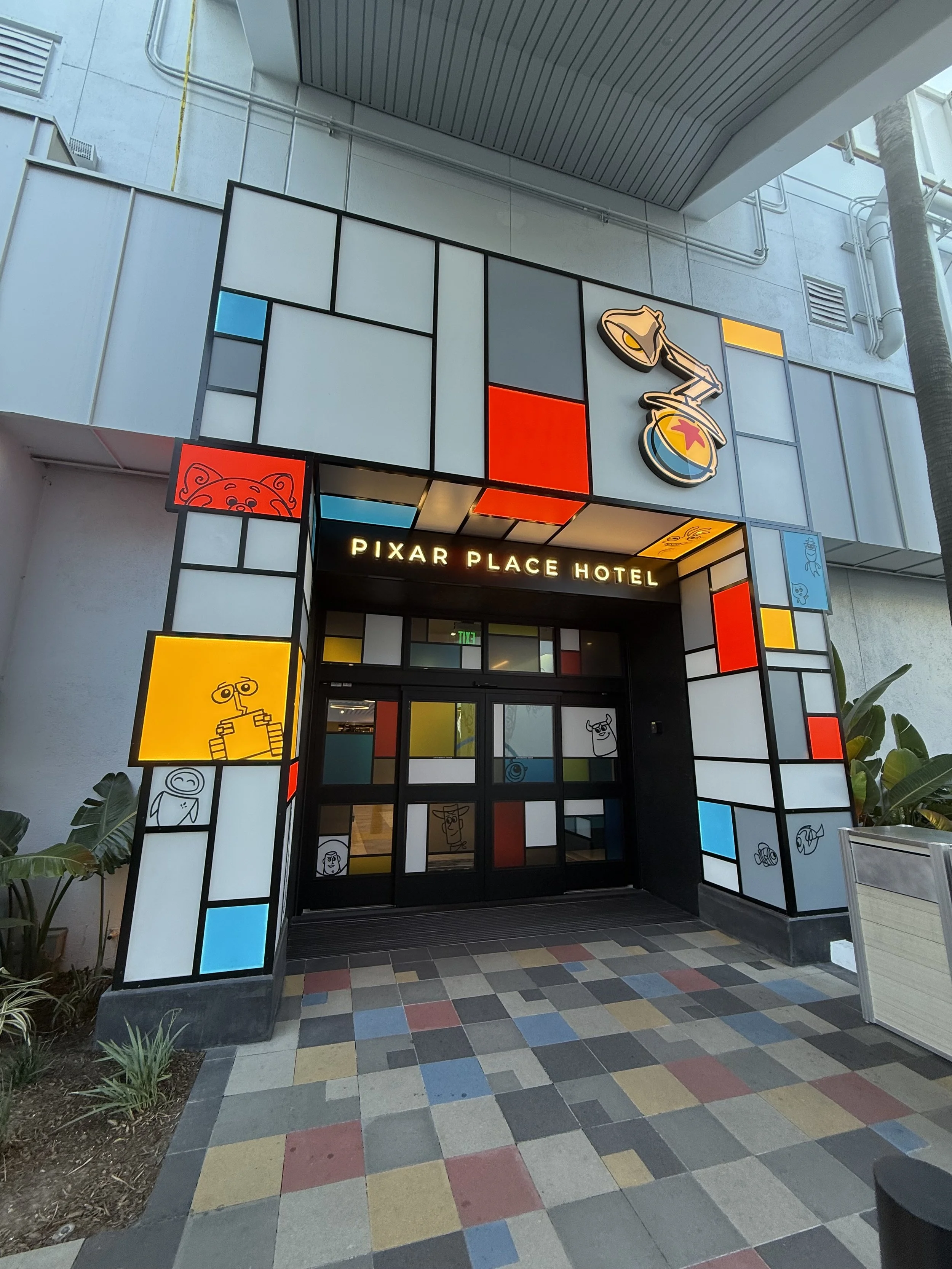 Entrance of Pixar Place Hotel with colorful stained glass design and Pixar icons.