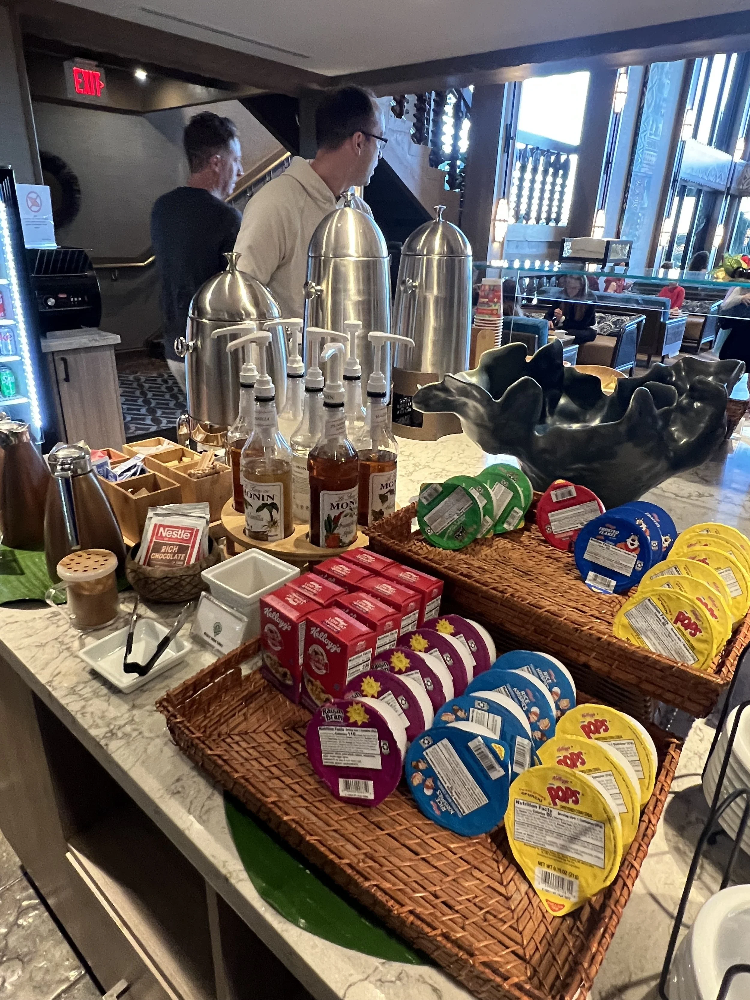 Breakfast buffet station with various spreads, syrups, and toppings on a marble counter in a restaurant or cafe.