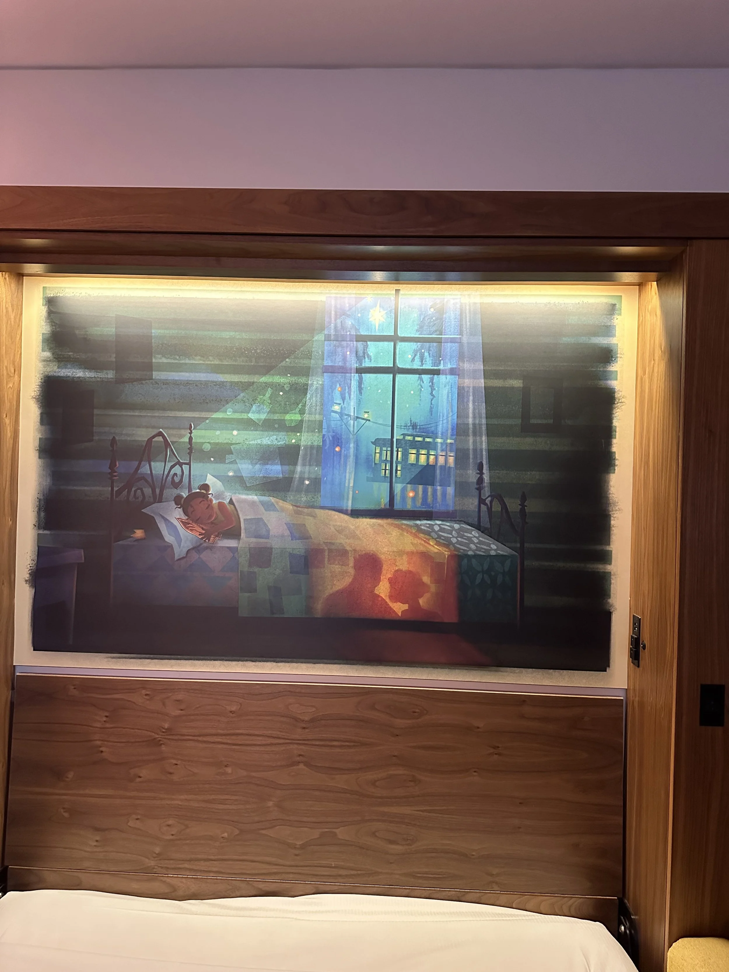 Wall art depicting a cozy bedroom scene with a girl sleeping in bed, colorful blankets, and two silhouetted figures engaged in conversation under a starry night sky seen through a window.