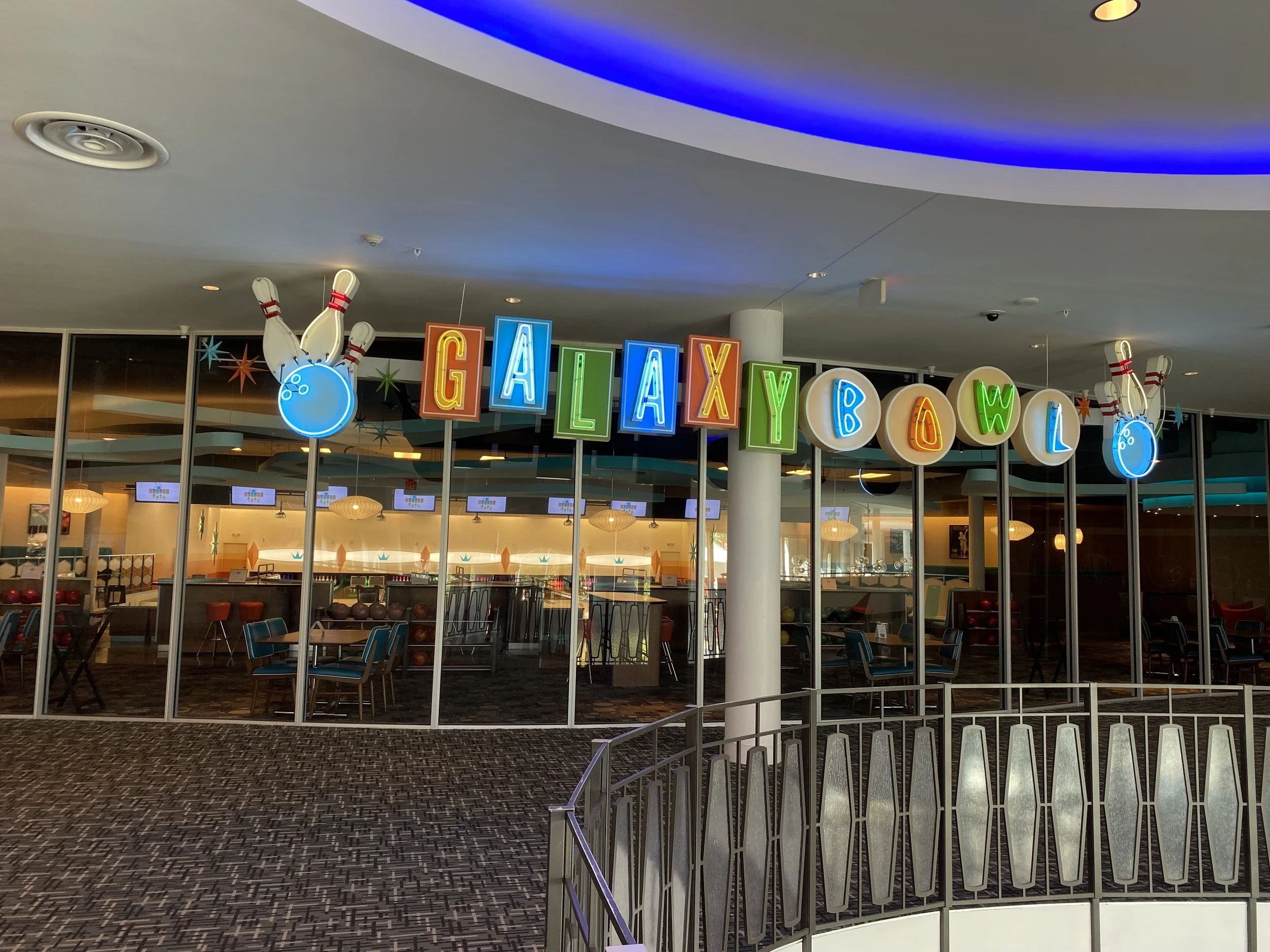 Colorful sign spelling out 'GALAXY BOWL' with neon letters and bowling ball and pin decorations in an entertainment center.