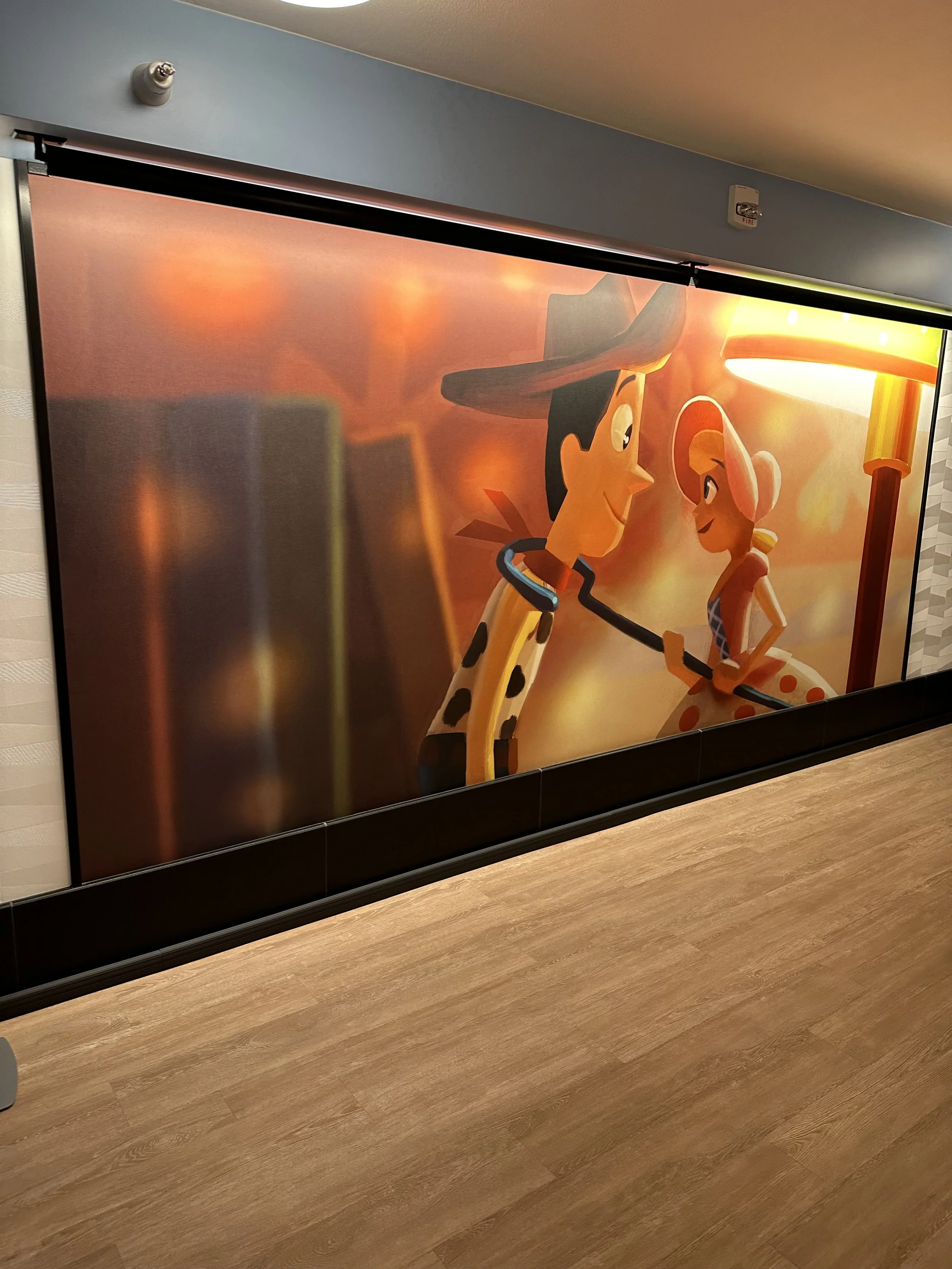 A large colorful mural of animated characters Woody and Bo Peep from Toy Story, sharing a friendly moment in a sunset scene.