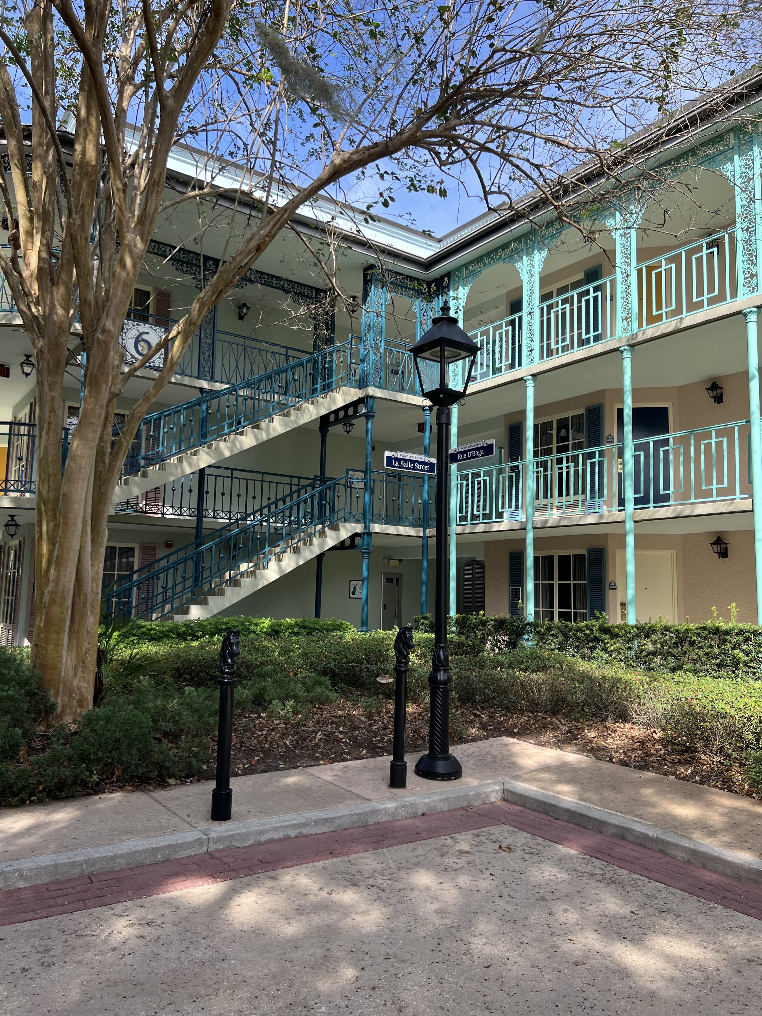 An apartment building with blue exterior balconies, a staircase, and signs indicating the intersection of La Salle Street and Rue D'Baga.