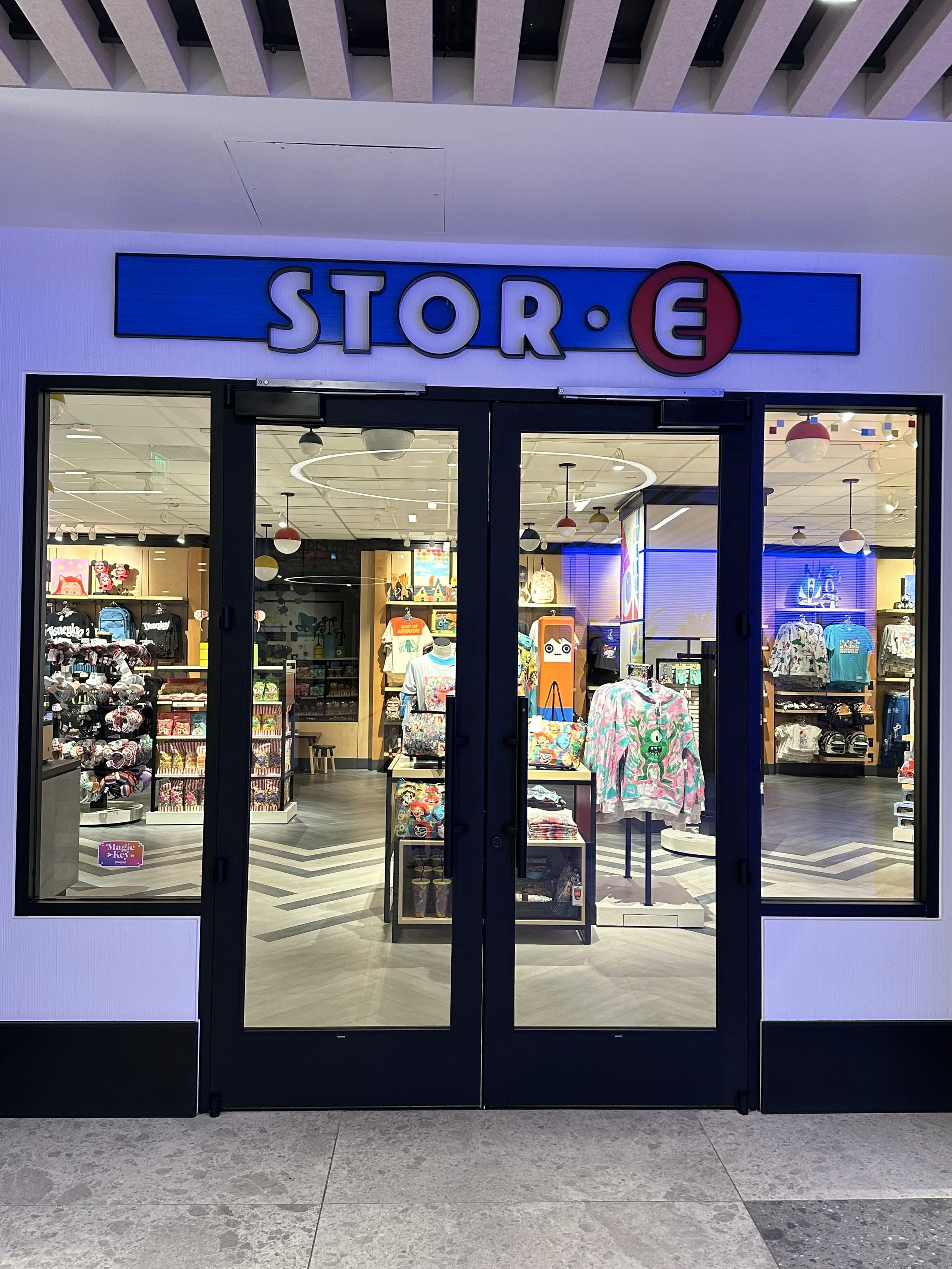 Entrance of a store with a blue sign reading 'STOR.E' and a collection of colorful merchandise including clothing and accessories visible inside.