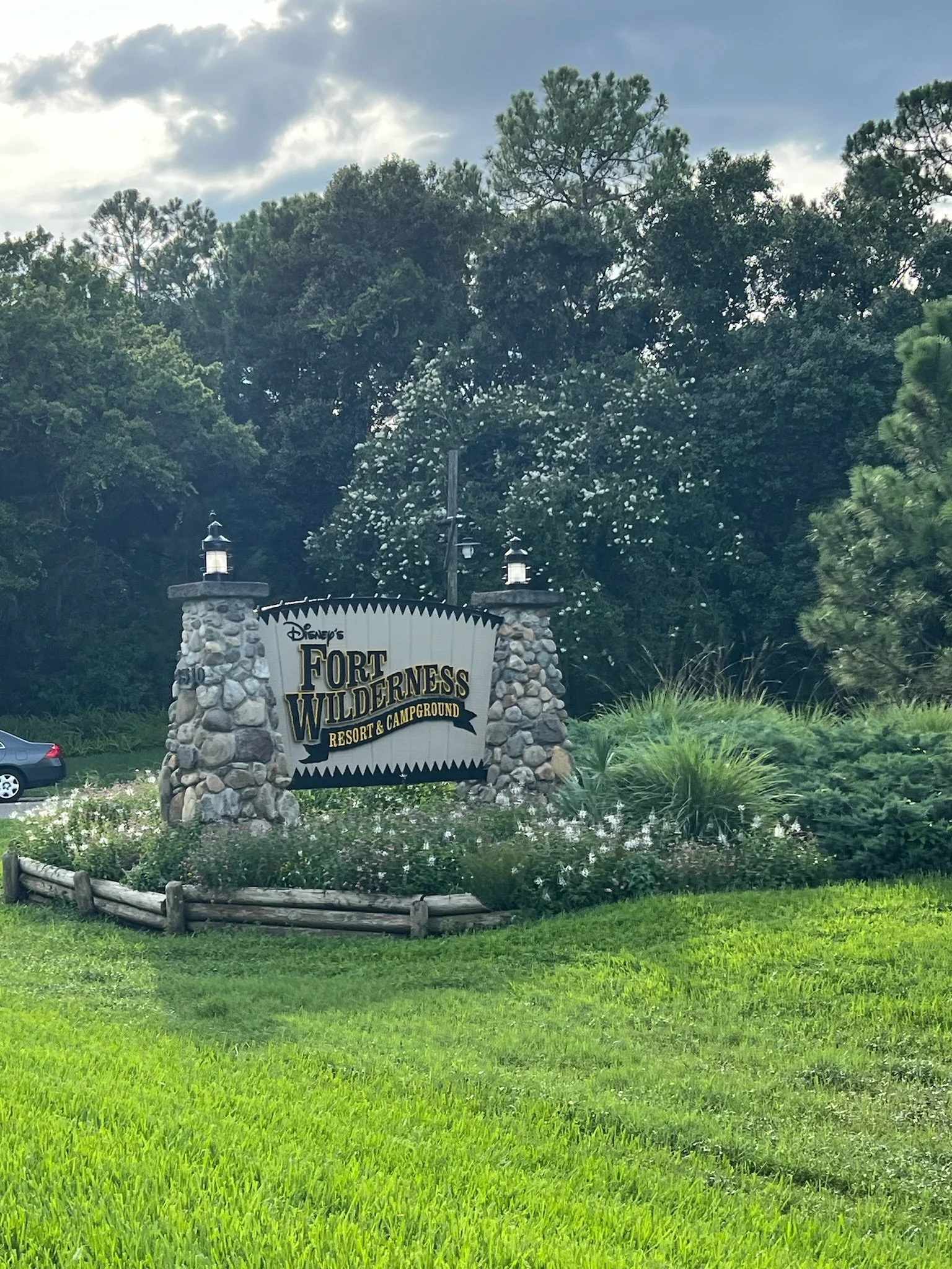 Sign for Disney's Fort Wilderness Resort & Campground surrounded by greenery and trees.