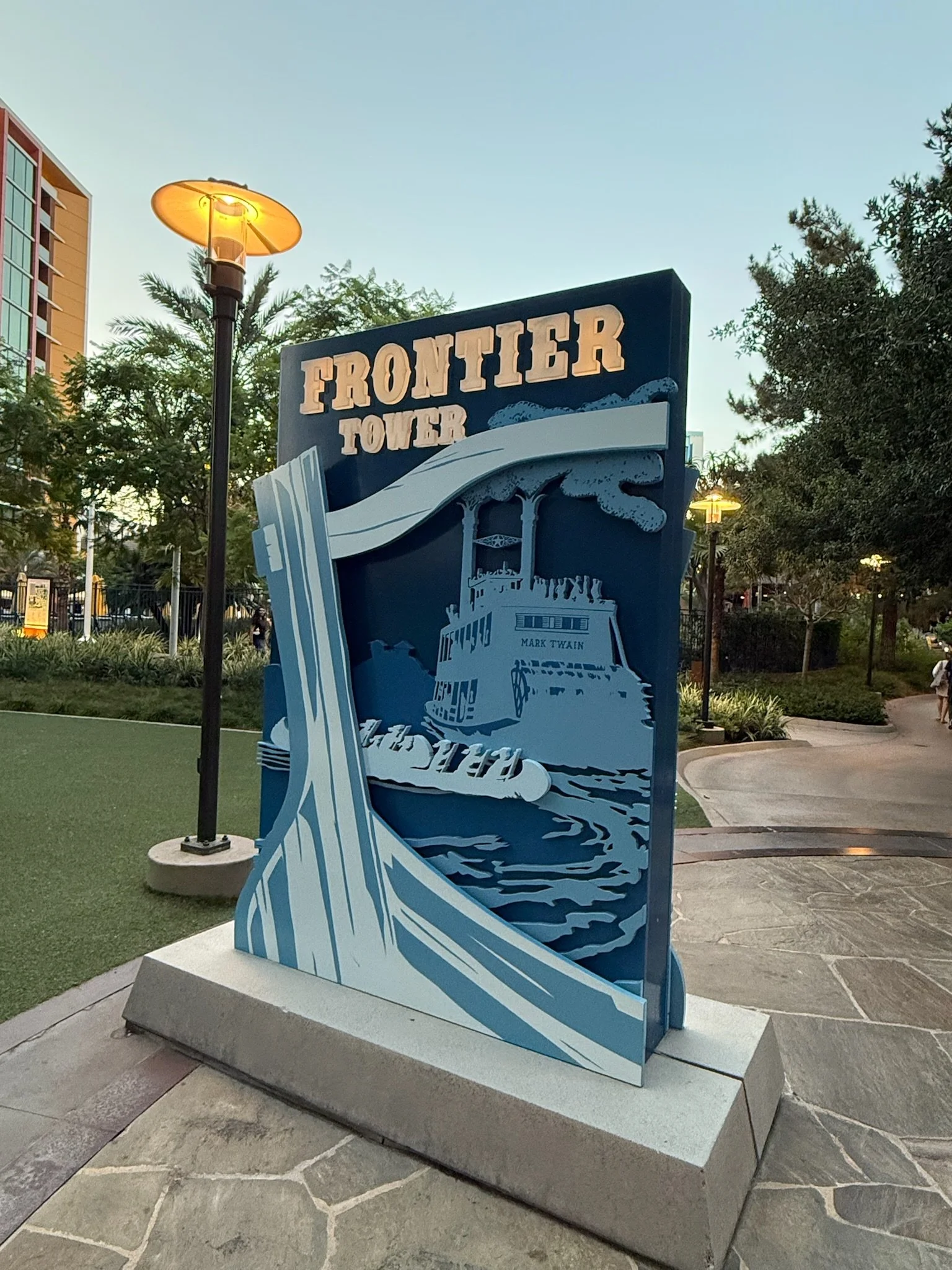 Sign for Frontier Tower depicting a stylized boat on water with steam and a open book with the text "Mark Twain".