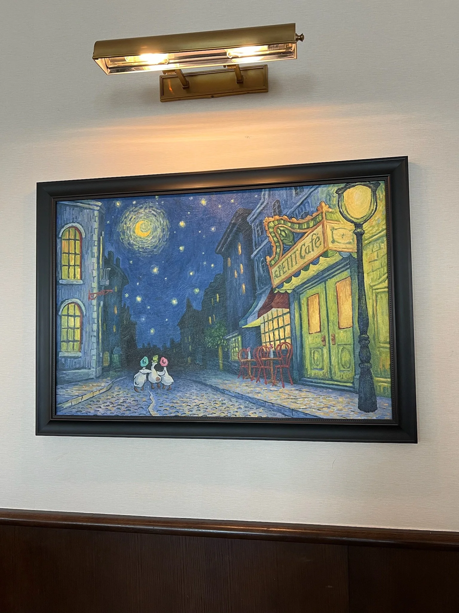 Painting of a nighttime street scene with a crescent moon and stars, two duck characters with hats walking, and a green cafe with outdoor tables, illuminated by a streetlamp.