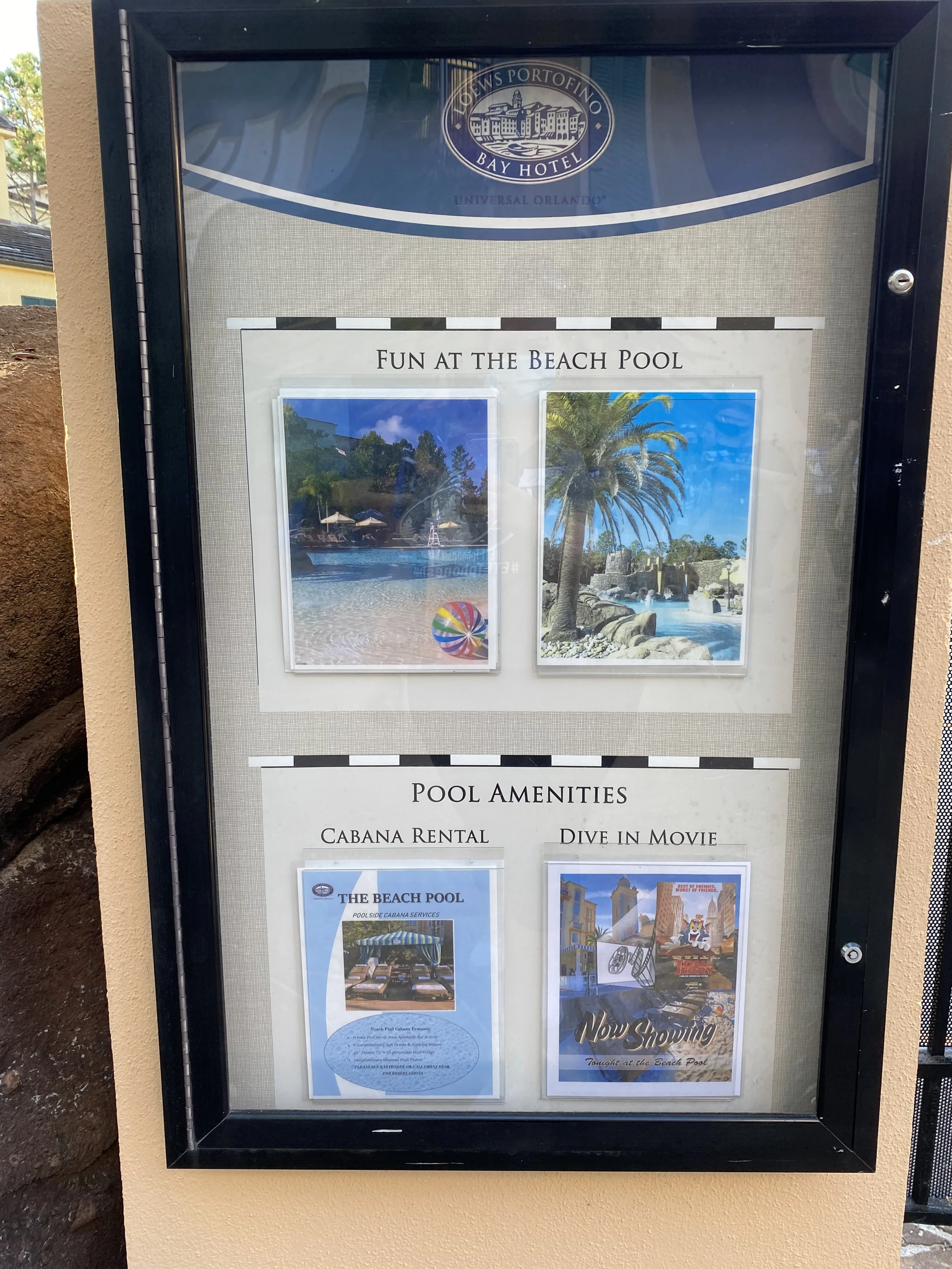 Signboard displaying information about the beach pool at the Fonteyn's Portofino Bay Hotel, featuring images of the pool area with palm trees and water. It promotes the pool's amenities, including cabana rental and a movie night.