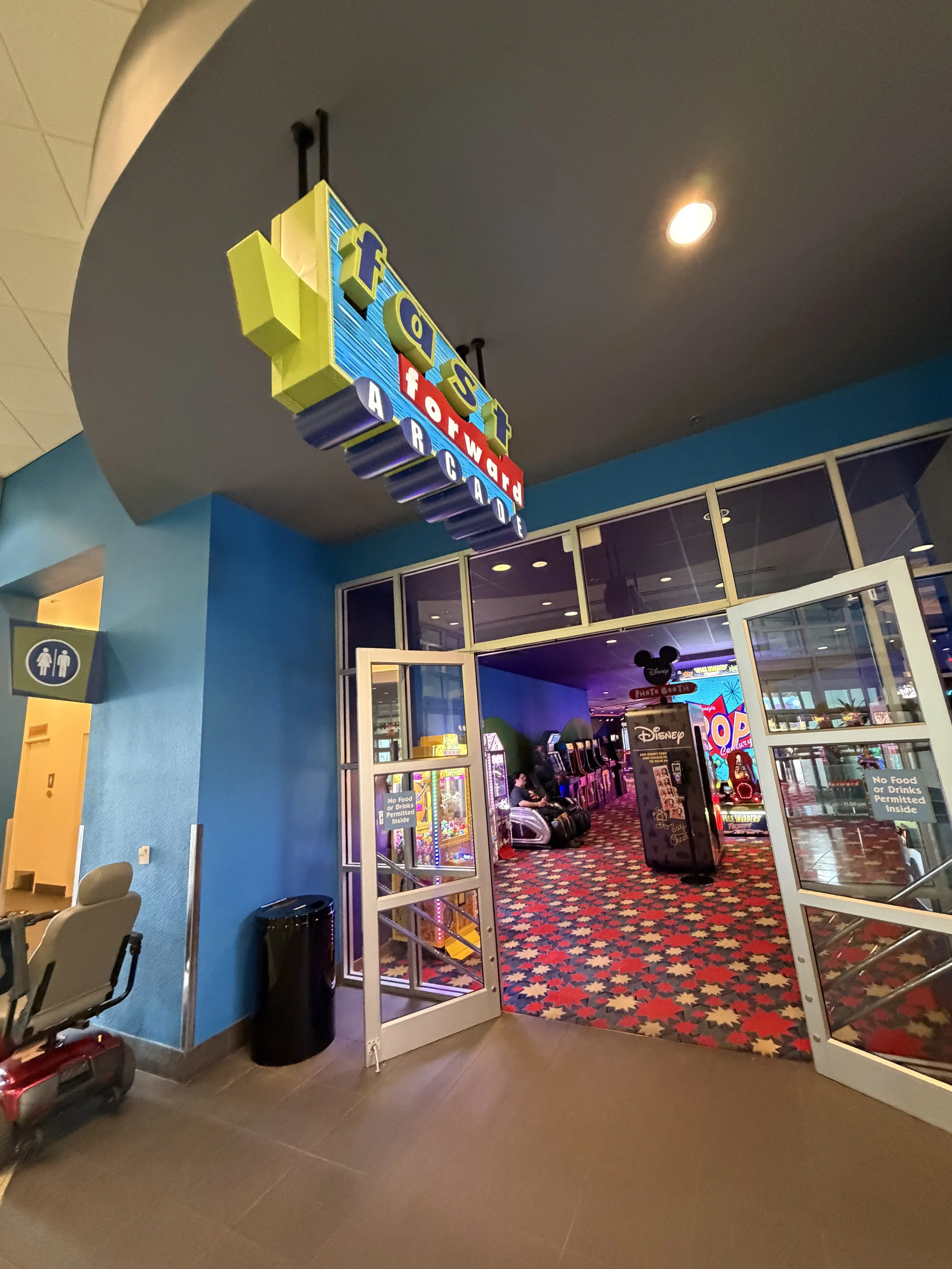 Entrance to an arcade area with a sign that reads 'Fabe Topward Arcade' and a brightly colored patterned carpet inside.