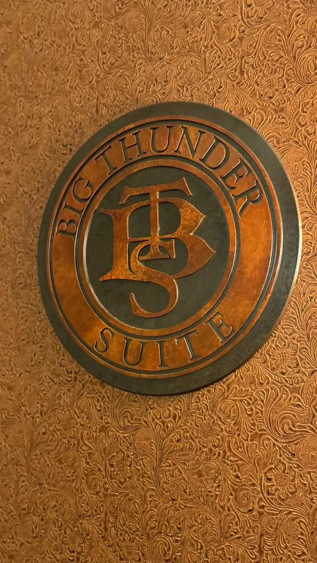 Decorative wall plaque reading 'Big Thunder Sutte' with a central emblem of stylized letters 'B' and 'T' in a textured gold and black design.