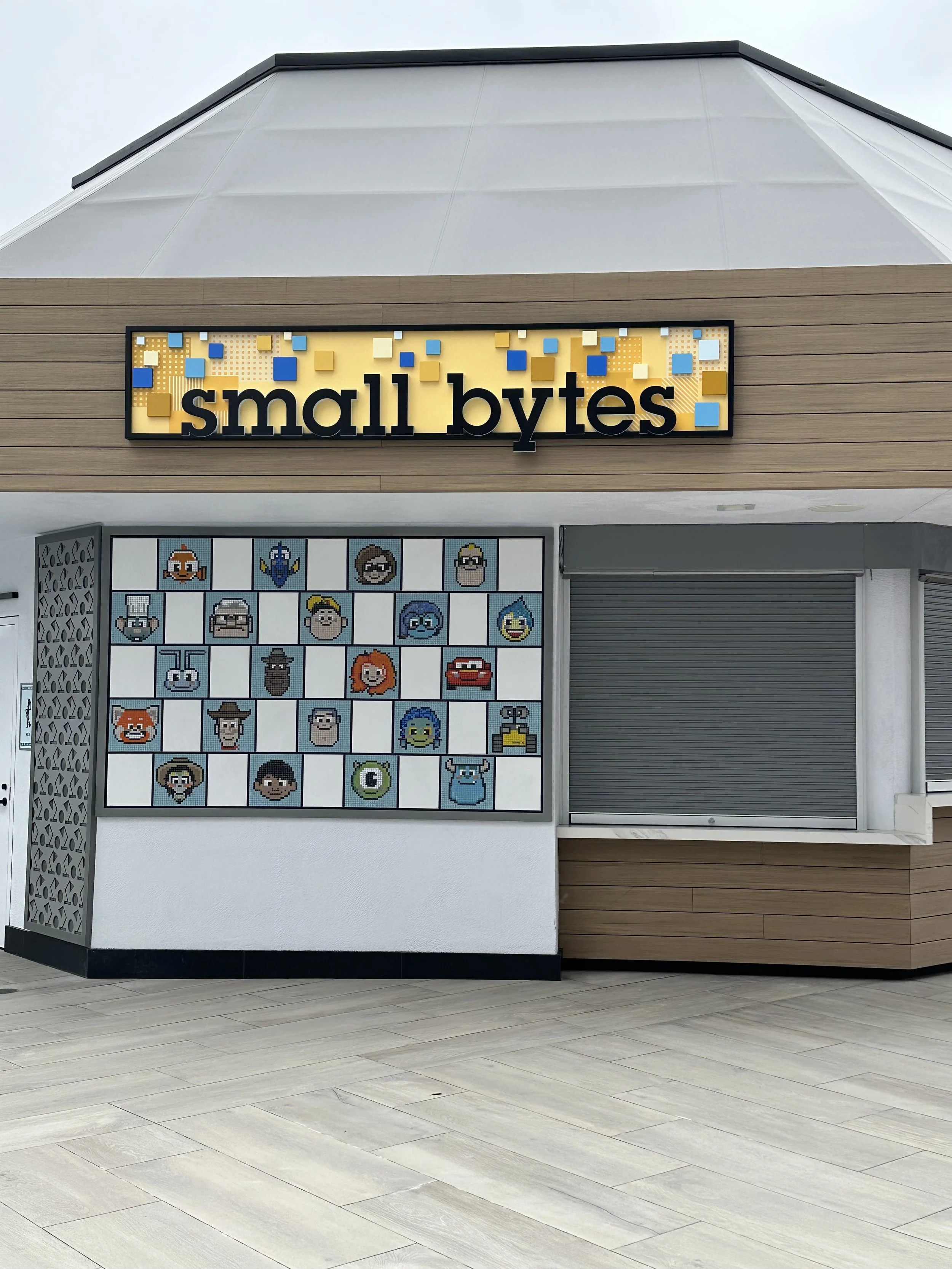 Exterior of a Small Bytes store with a pixel art mosaic of animated characters and a sign with small colored blocks.