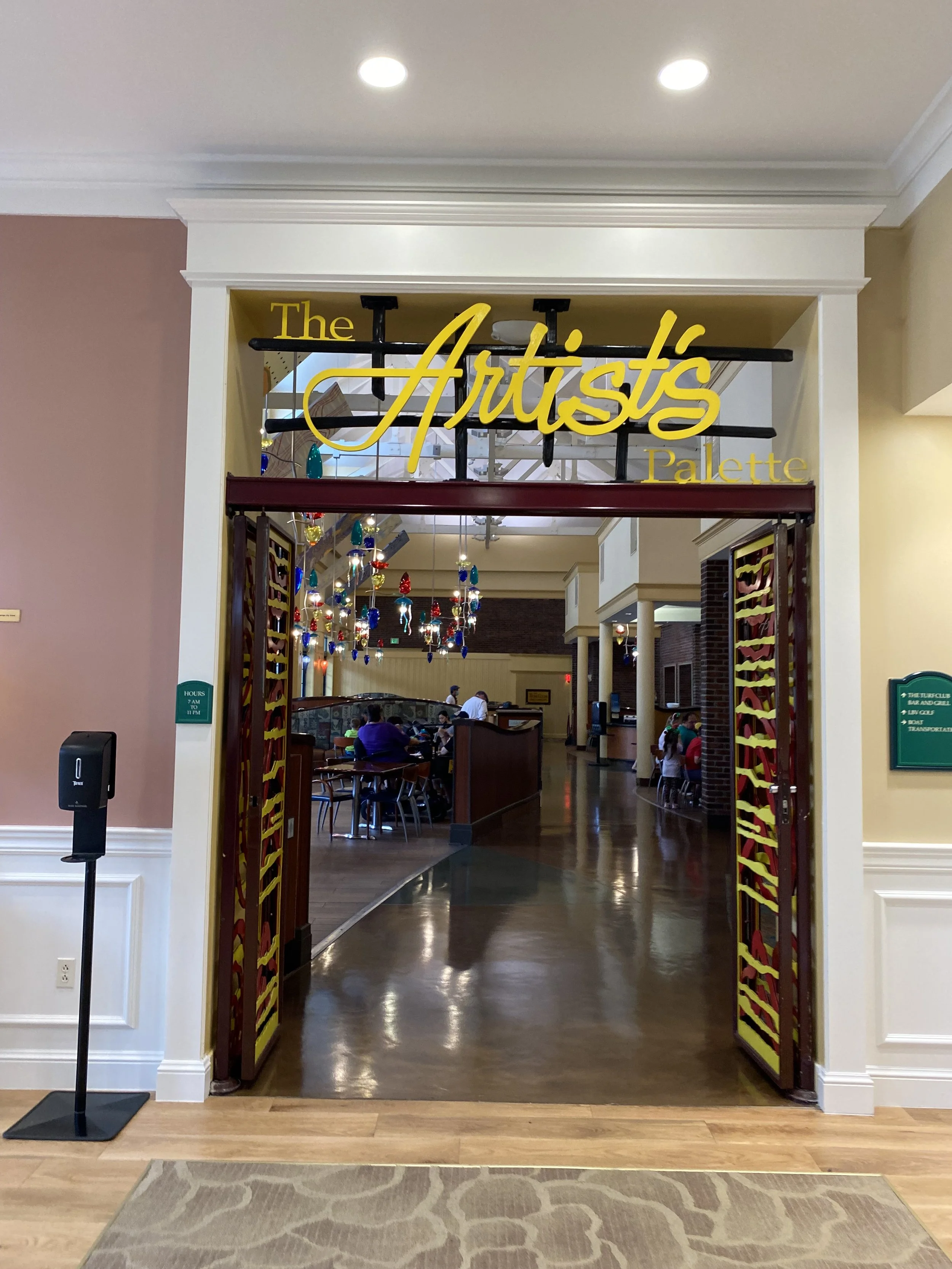 Entrance to The Artist's Palette restaurant with colorful hanging lights and patrons inside.