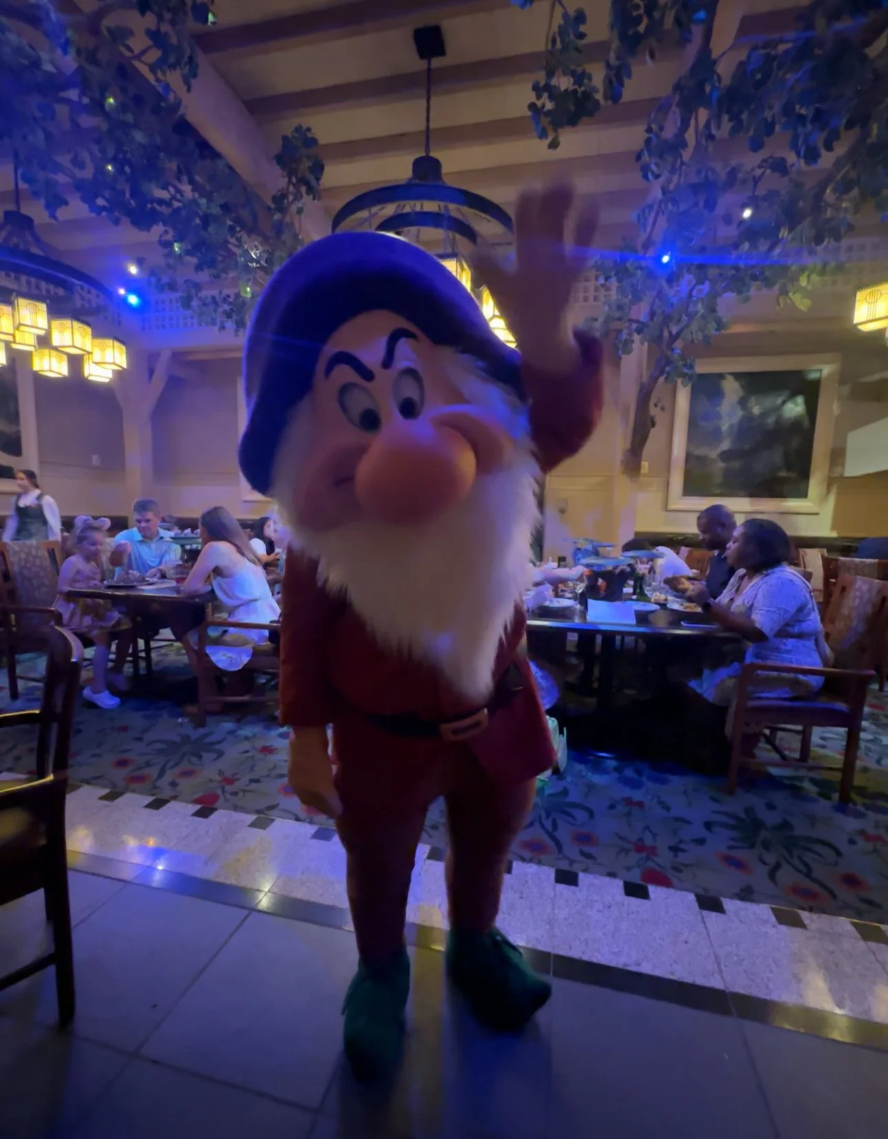 Mickey Mouse mascot in a restaurant with people dining in the background.