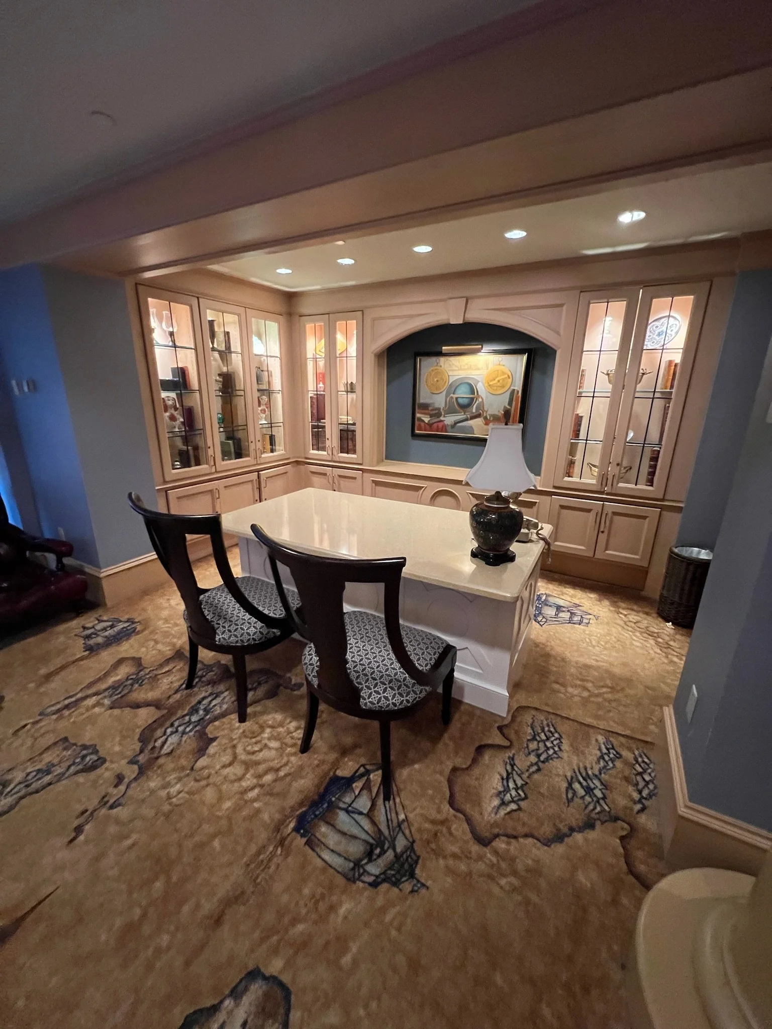 Dining room with built-in wood cabinetry, a large island with a lamp, two chairs, and a patterned carpet.