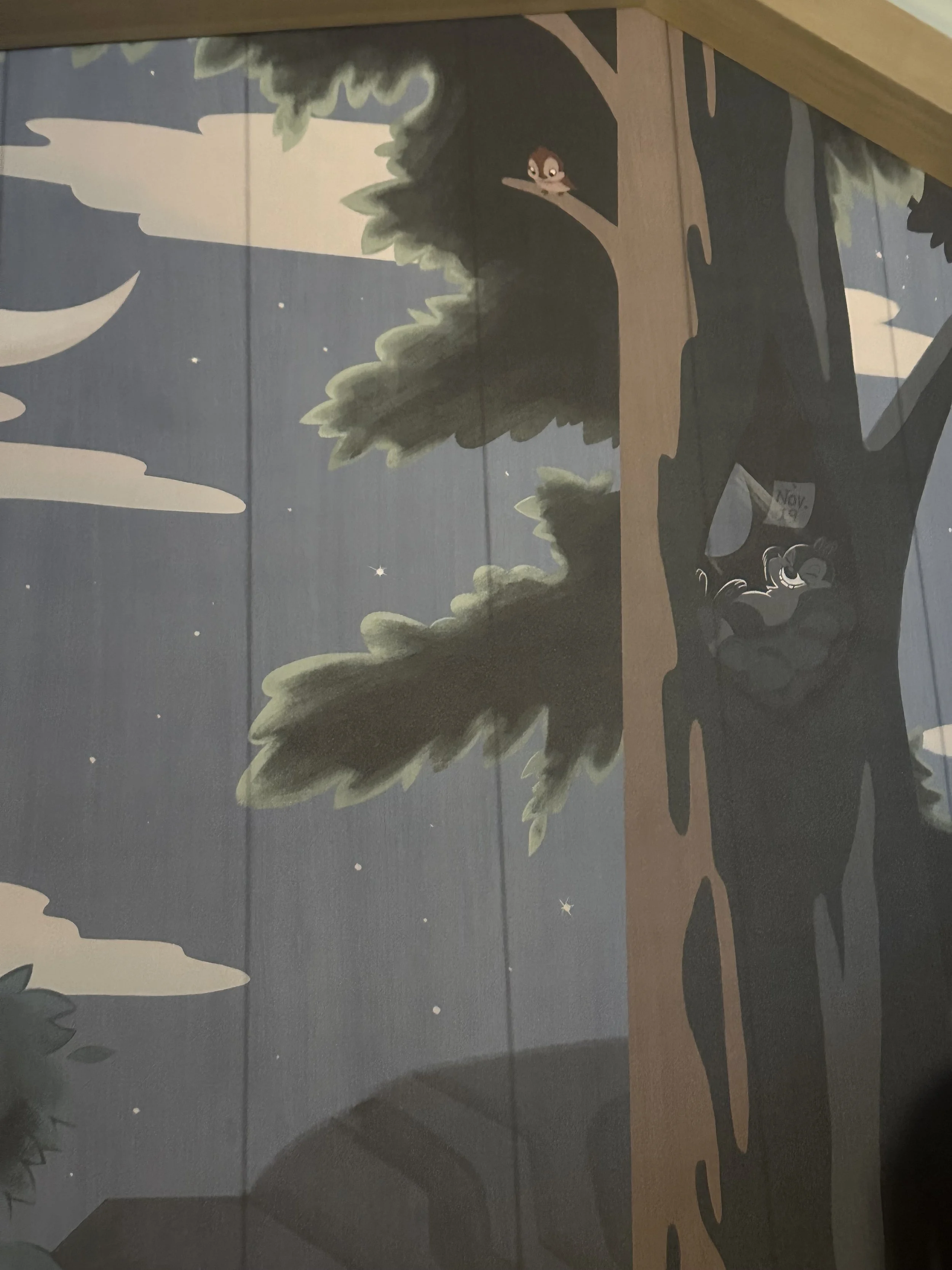 Illustration of a nighttime scene with a large tree, stars, a moon, and two cartoon animals: an owl perched on a branch and a raccoon sitting in a hollow of the tree.